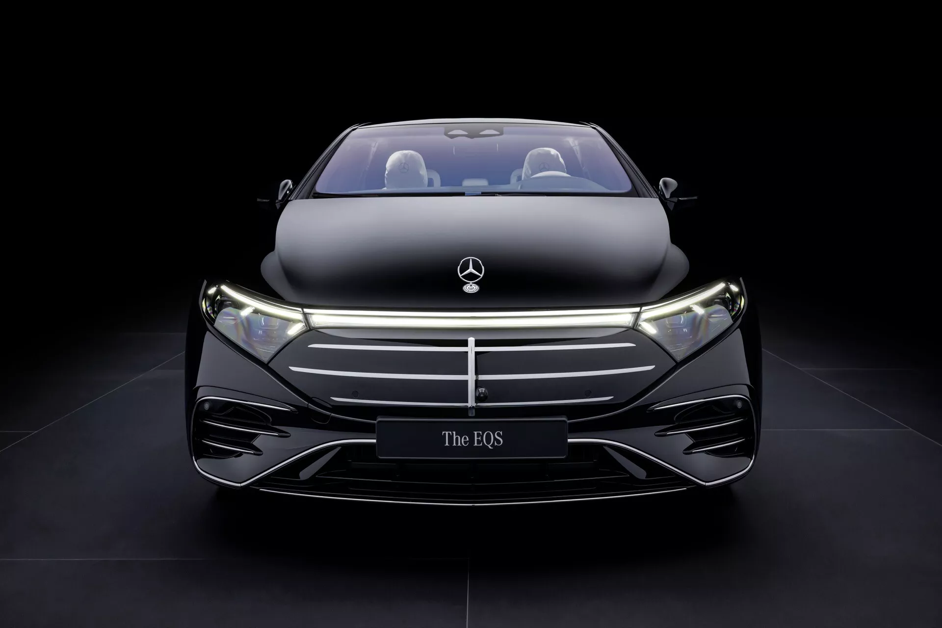 Modèle Mercedes-Benz EQS 297 facelift 2024 présentant son design avant élégant avec grille fermée, phares LED et finition hautement brillante sur fond sombre, soulignant le luxe et la technologie avancée des véhicules électriques