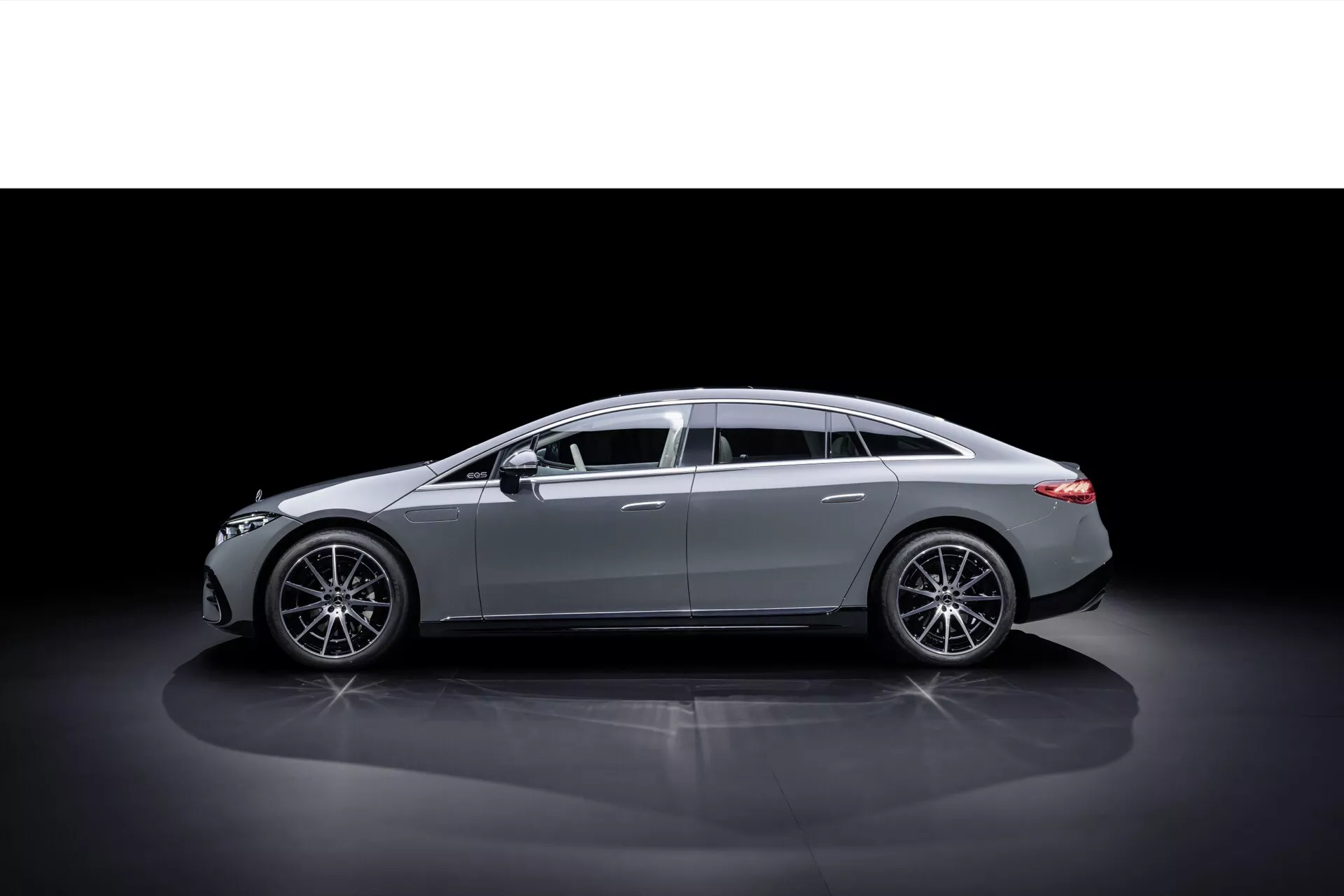Vue de profil de la Mercedes-Benz EQS 2024 après facelift sur fond sombre mettant en valeur un design élégant et des lignes de carrosserie, avec des roues en alliage modernes et des accents de chrome de luxe