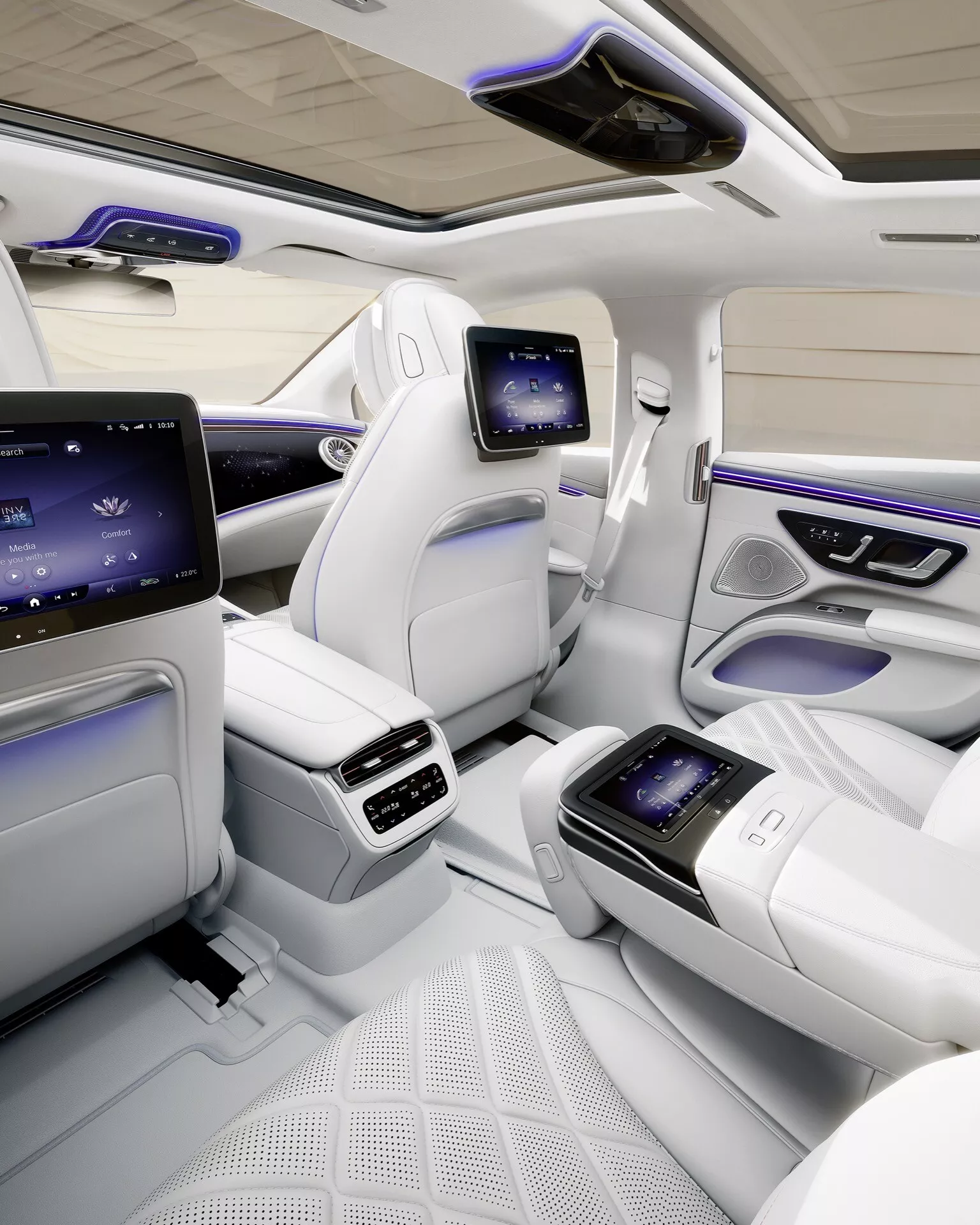 Vue intérieure de la Mercedes-Benz EQS 2024 montrant la zone de la cabine arrière luxueuse avec des sièges en cuir premium, des écrans tactiles intégrés sur la console centrale, un éclairage d'ambiance et un toit panoramique