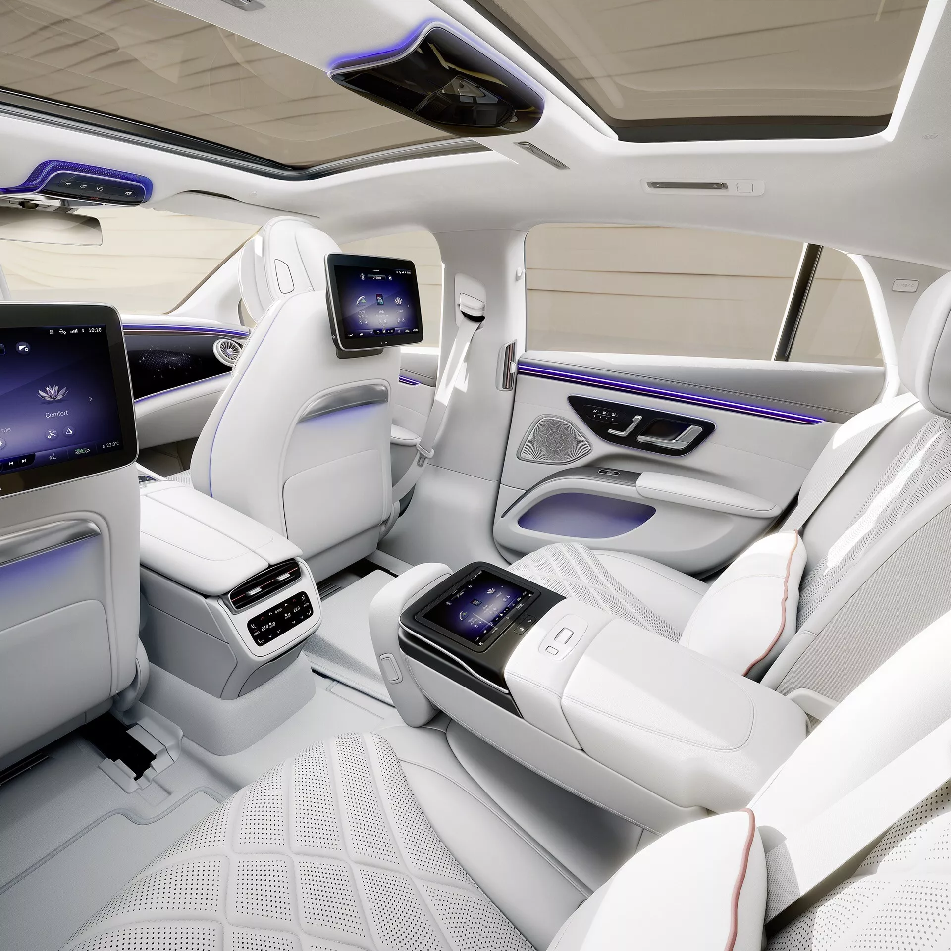 Intérieur du Mercedes-Benz EQS Facelift 2024 présentant la cabine arrière de luxe depuis une vue en plongée, avec des sièges individuels profilés en cuir blanc matelassé, console centrale intégrée avec écran tactile, écrans dédiés au divertissement arrière, contrôle climatique avancé, éclairage d'ambiance, toit panoramique et améliorations riches en technologie pour un confort et un luxe exceptionnels des passagers.