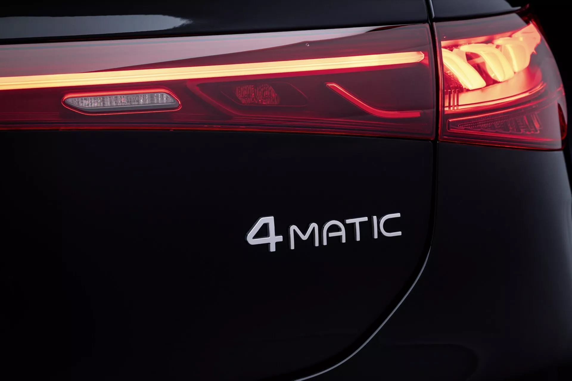 Gros plan sur l'arrière de la Mercedes-Benz EQS 2024 mettant en lumière le design du feu arrière LED et le badge 4MATIC sur une carrosserie de couleur sombre