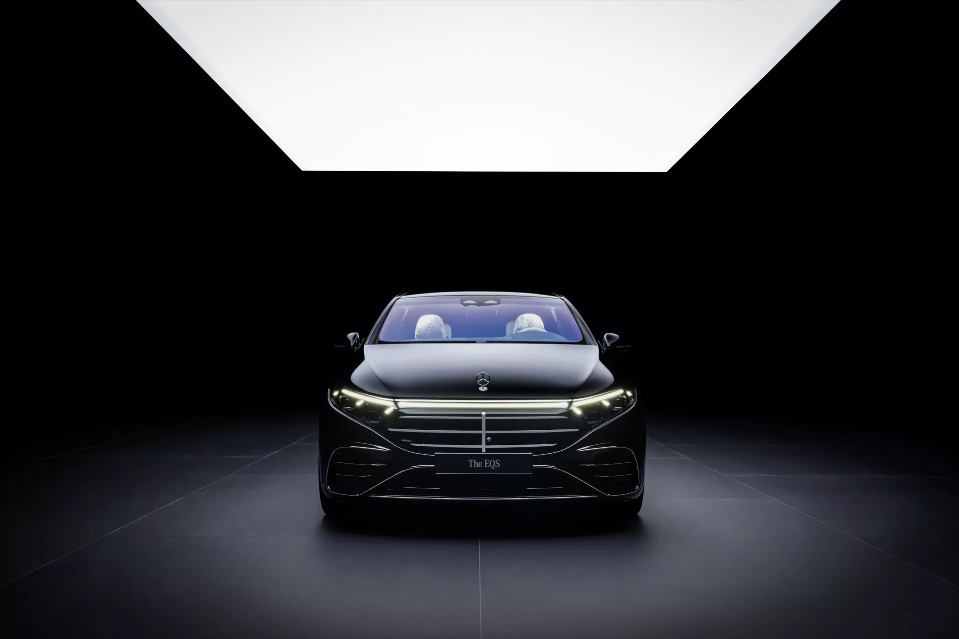 Modèle restylé de Mercedes-Benz EQS 2024 présenté de manière proéminente, mettant en lumière la grille, les phares et le design avant élégant, souligné par un éclairage doux venant du haut sur un fond sombre, capturant l'essence du luxe et de l'artisanat automobile moderne.