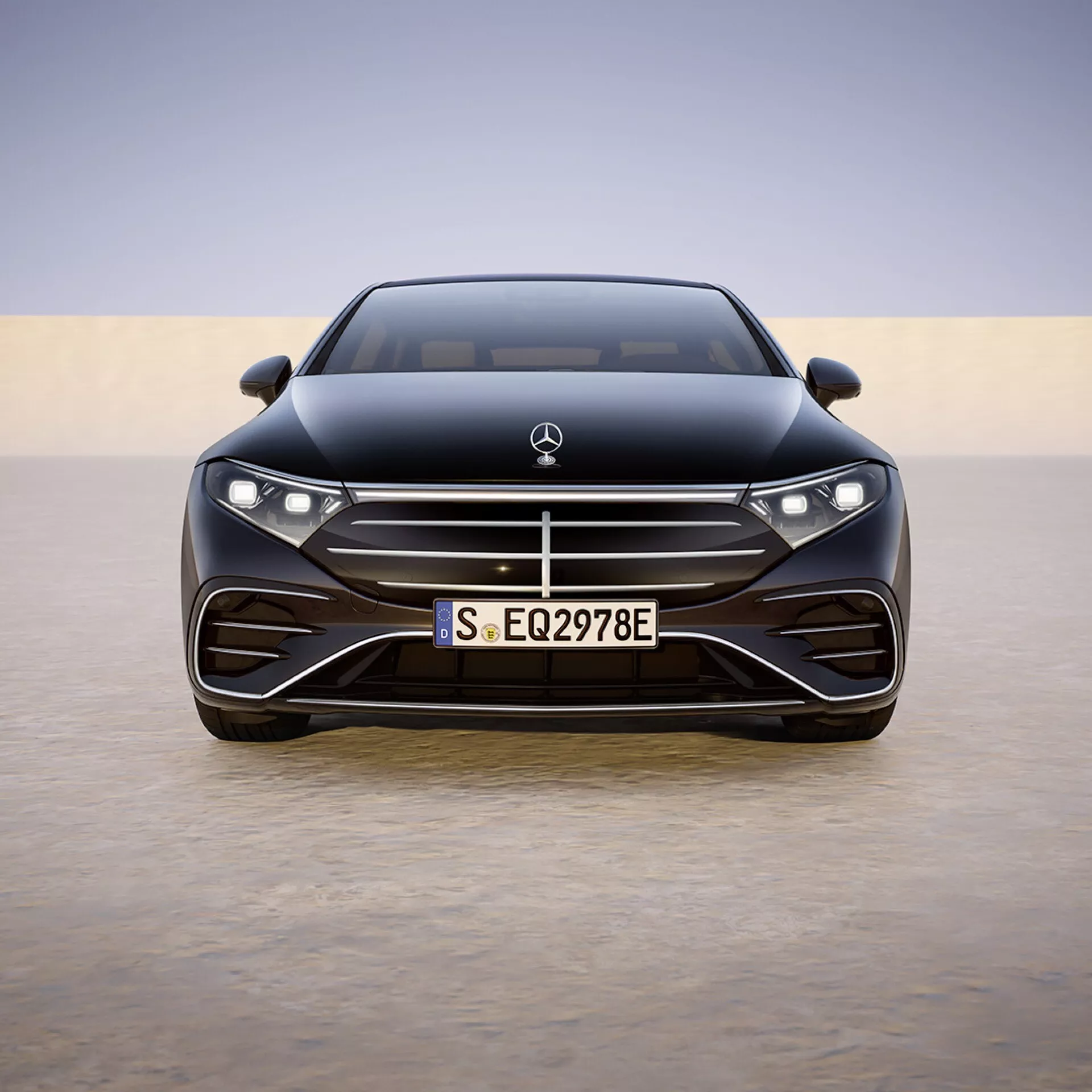 Vue de face de la Mercedes-Benz EQS 2024 (297-facelift) montrant la largeur complète et les détails de conception tels que les phares LED, le logo du fabricant, le pare-chocs avant orienté performance avec de grandes entrées d'air, plaque d'immatriculation européenne, lignes aérodynamiques du capot et systèmes avancés d'aide à la conduite intégrés dans la zone de la grille sur un fond en dégradé doux.