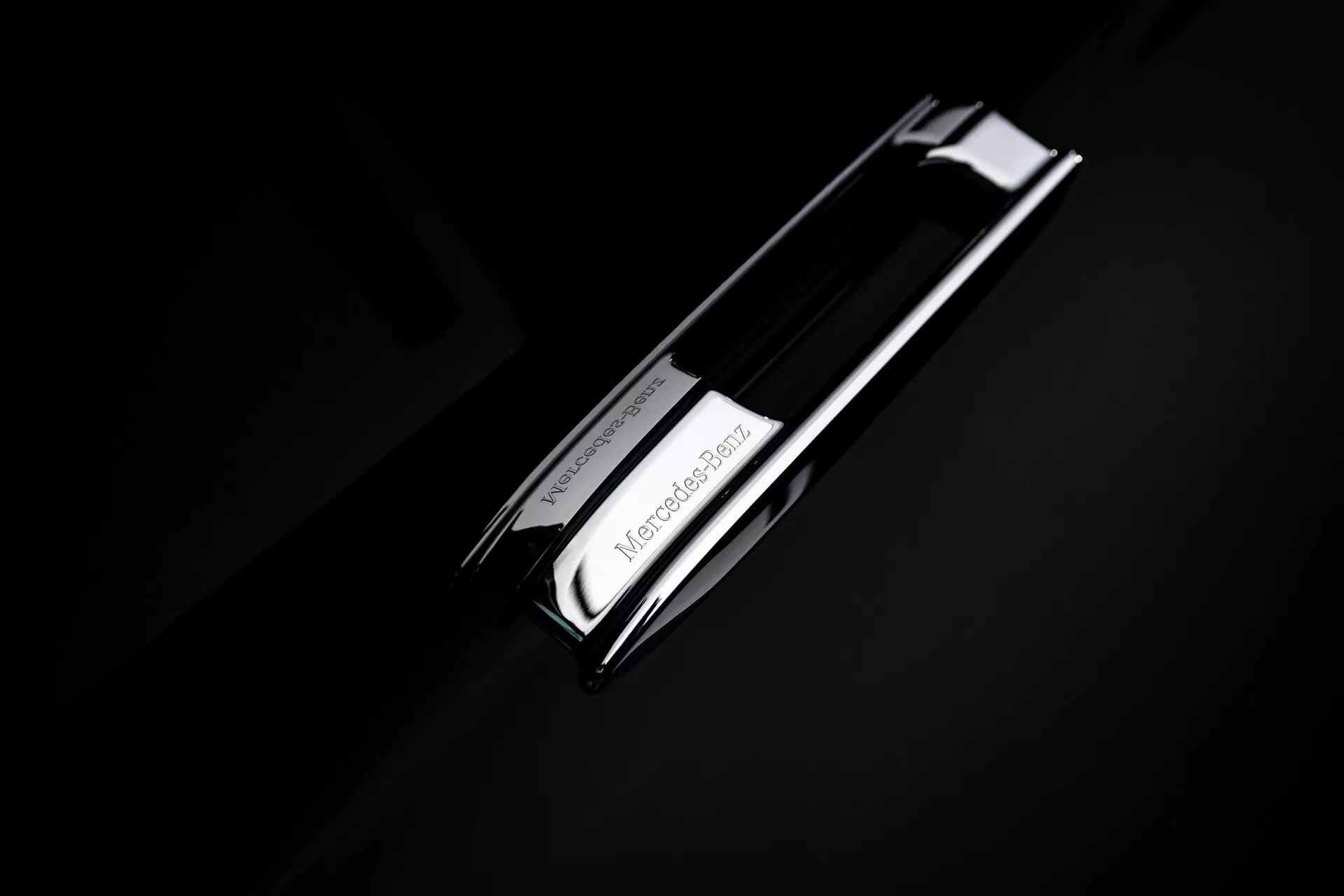 Vue rapprochée de l'emblème de Mercedes-Benz EQS 2024 (297-facelift) avec le logo étoilé à trois pointes en chrome sur un fond sombre, soulignant le design automobile de luxe de la marque.