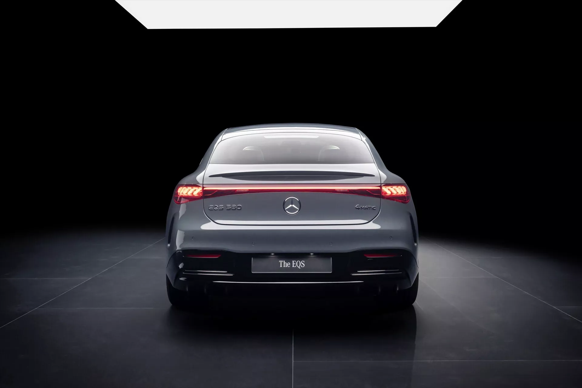 Vue arrière de la Mercedes-Benz EQS 2024 présentant des feux arrière LED élégants, des accents chromés et un design sophistiqué dans un éclairage de studio