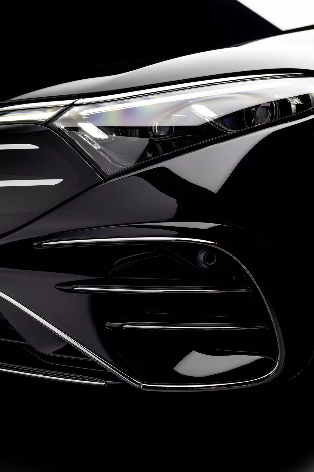 Vue rapprochée du facelift de la Mercedes-Benz EQS 2024 présentant les caractéristiques détaillées du phare, de la calandre et du pare-chocs, mettant en lumière le design aérodynamique de la voiture et la technologie d'éclairage avancée