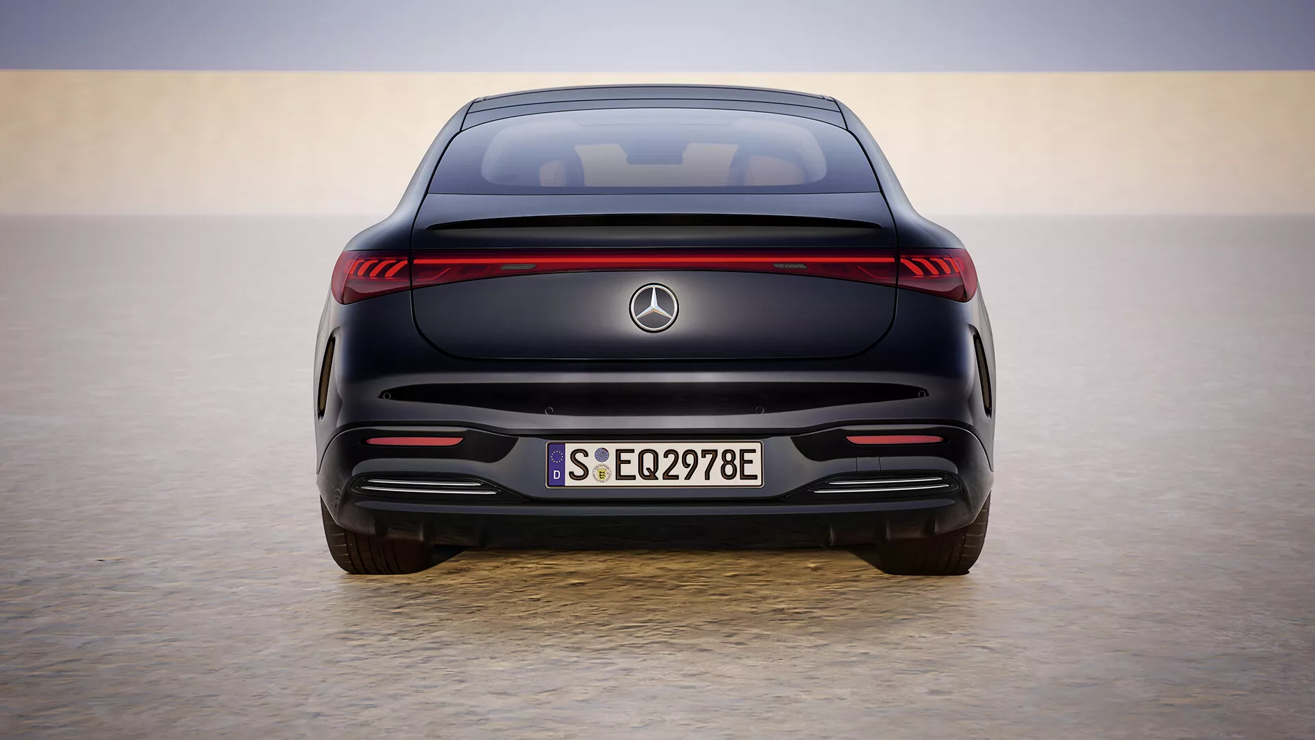 Vue arrière du modèle Mercedes-Benz EQS 297 facelift de 2024 contre un horizon en dégradé, mettant en avant son design de véhicule électrique avec bande lumineuse LED, plaque d'immatriculation européenne S EQ2978E, sans échappement et capteurs d'assistance au stationnement.
