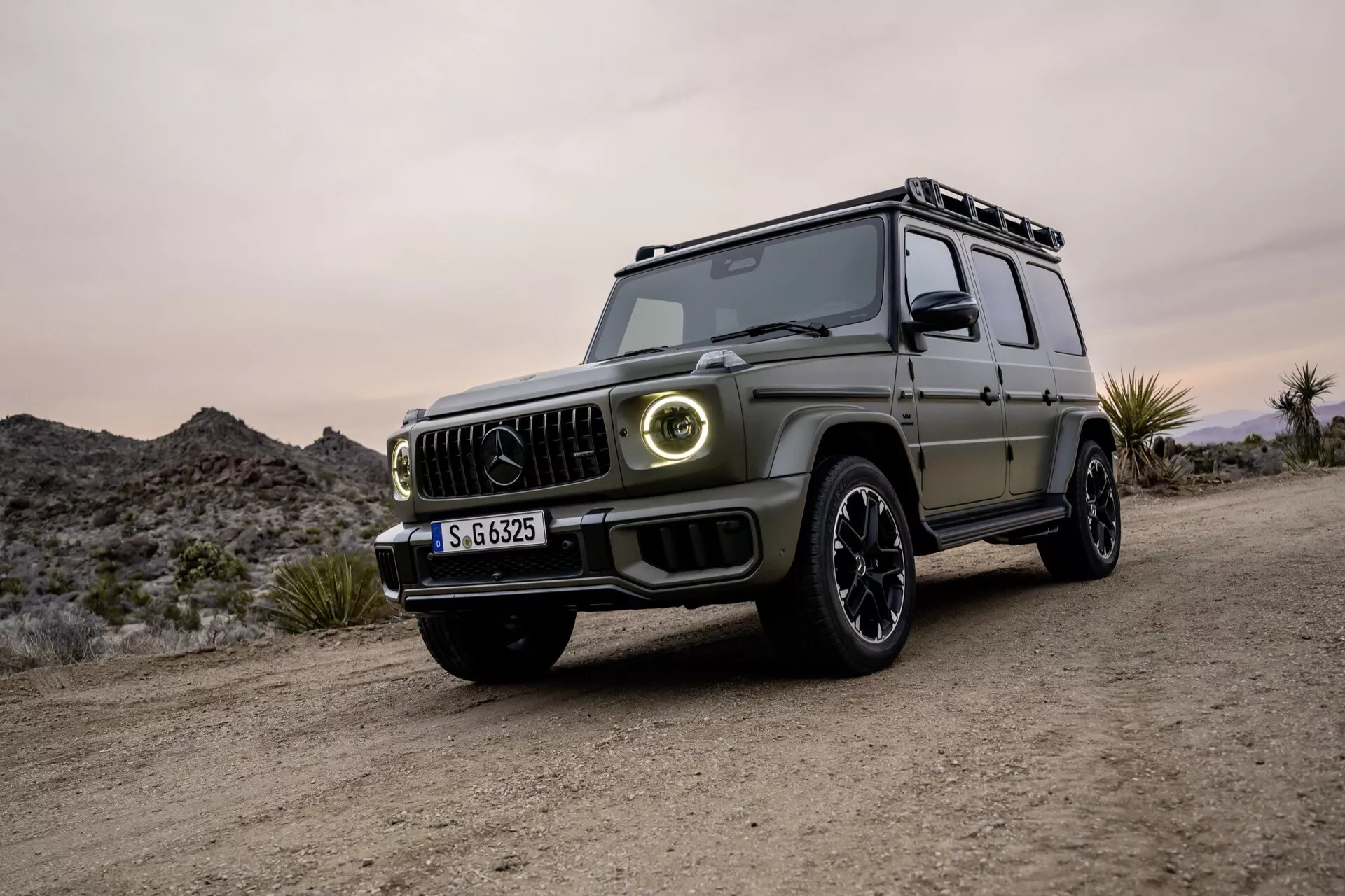 SUV de luxe Mercedes-Benz Classe G 2024 en vue trois quarts avant, présentant un design moderne, phares LED et capacités tout-terrain sur une surface non pavée