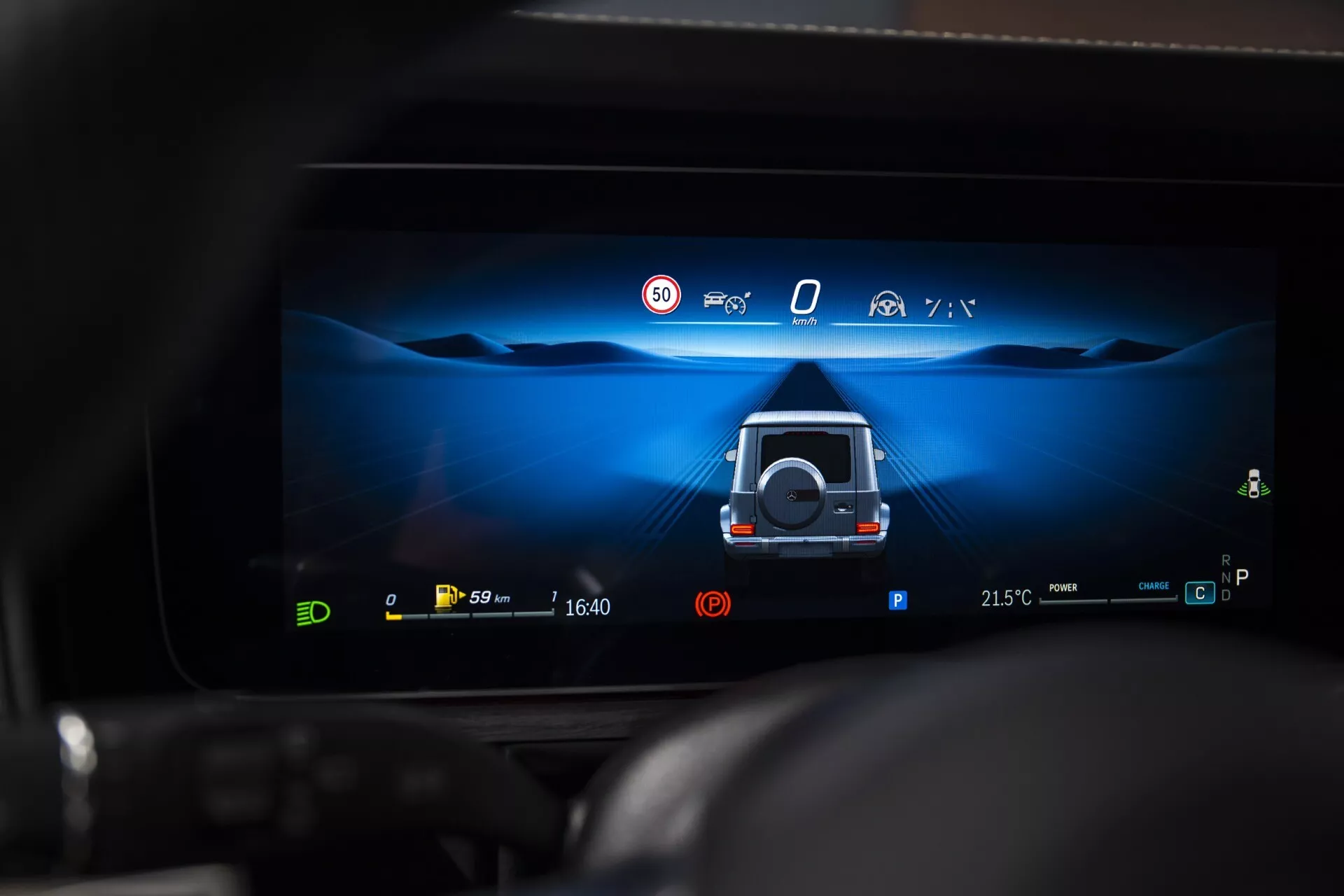 Affichage du tableau de bord numérique de la Mercedes-Benz G-Klasse 2024 montrant une vue d'assistance au stationnement à 360 degrés avec des caractéristiques de sécurité actives et des indicateurs de groupe motopropulseur électrique