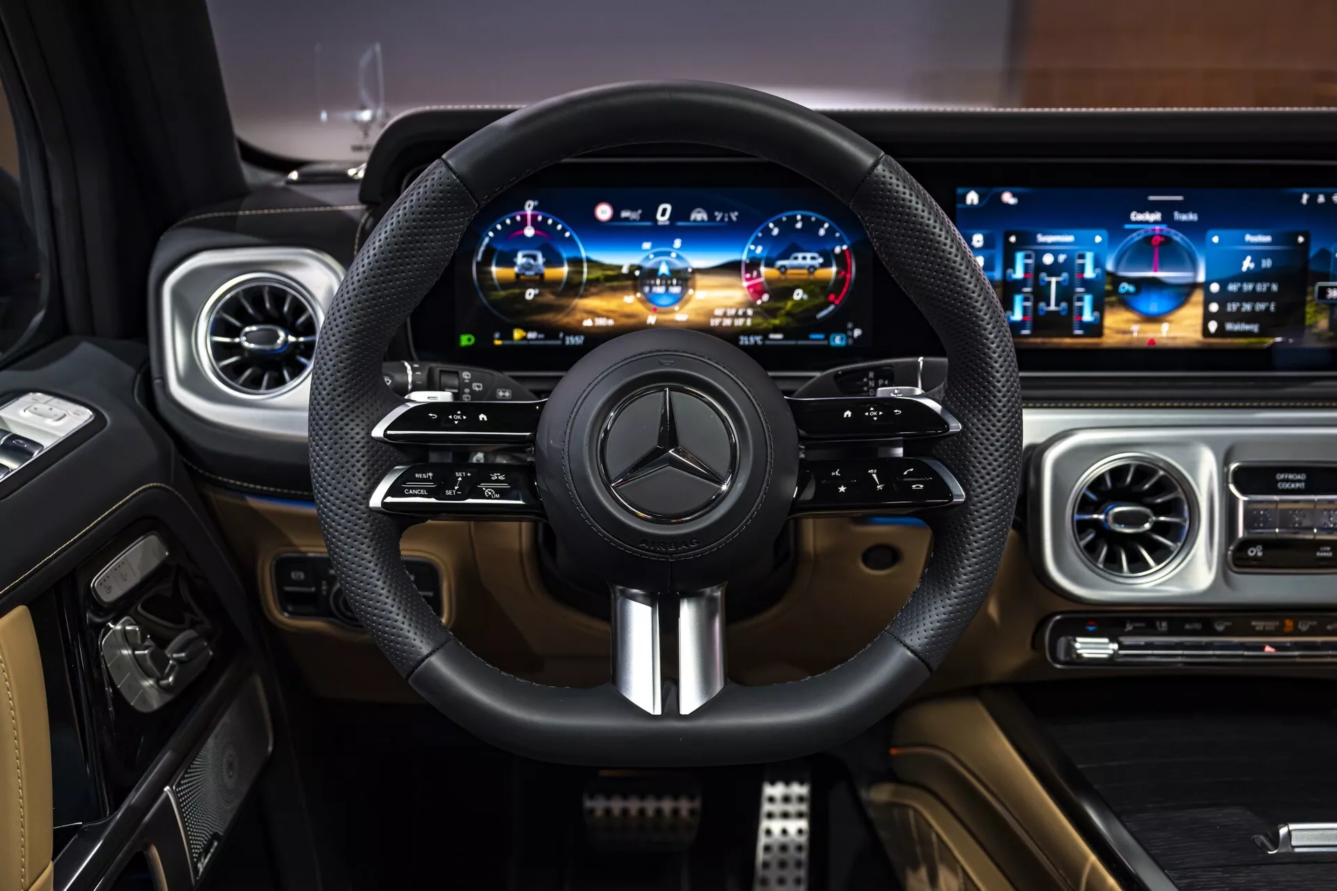 Intérieur de la Mercedes-Benz Classe G (G-Klasse) 2024 montrant le tableau de bord de luxe du point de vue du conducteur, comprenant un volant enveloppé de cuir avec emblème Mercedes et accents métalliques, tableau de bord numérique et panneau d'infodivertissement large