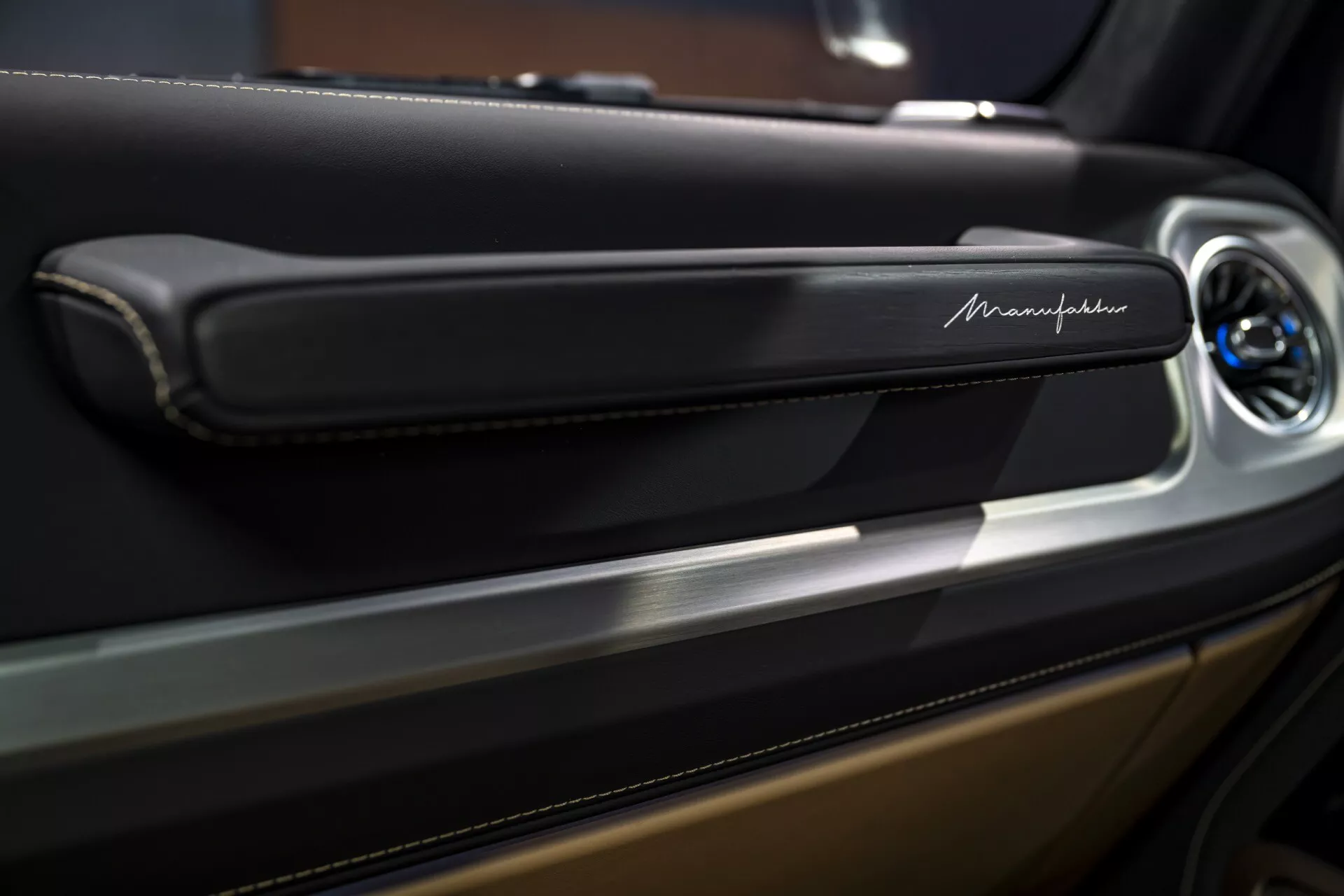 Vue rapprochée d'un panneau de porte Maserati mettant en lumière la poignée de porte élégante et moderne avec une finition métallique et un bouton de contrôle potentiel, soulignant les détails de luxe de l'intérieur.