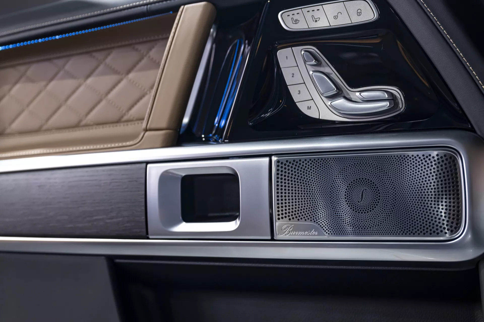 Vue rapprochée de l'intérieur d'une Mercedes-Benz G-Klasse 2024, mettant en lumière le cuir luxueux à piqûres diamantées, les finitions métalliques et la grille du haut-parleur haut de gamme dans la console centrale sous un angle oblique