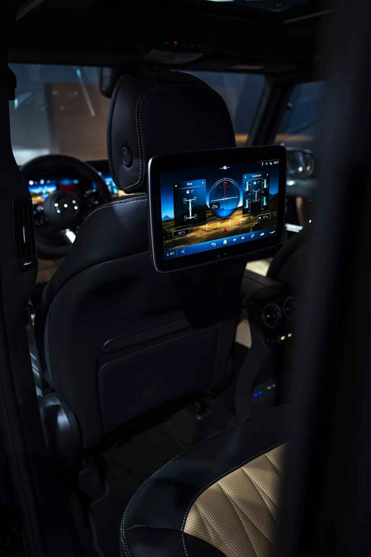 Intérieur de la Mercedes-Benz Classe G 2024 mettant en vedette le compartiment passager arrière avec un écran de divertissement haute résolution, une sellerie en cuir luxueux et un éclairage d'ambiance