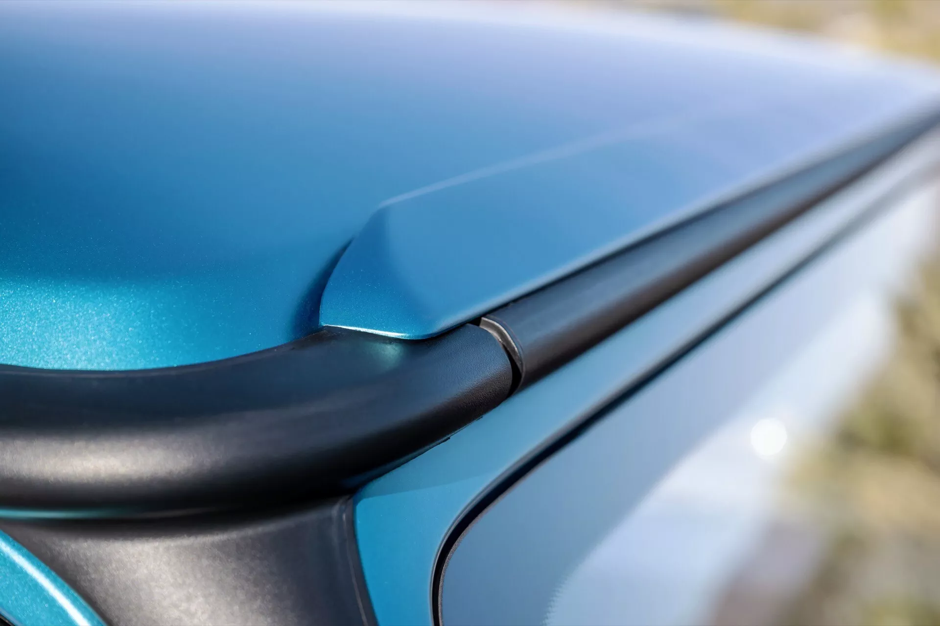 Gros plan sur une Mercedes-Benz Classe G 2024 en bleu métallique brillant, mettant en avant la carrosserie sans jointure et la finition haute brillance au niveau d'une jonction de panneau avec un élément de design noir contrastant.