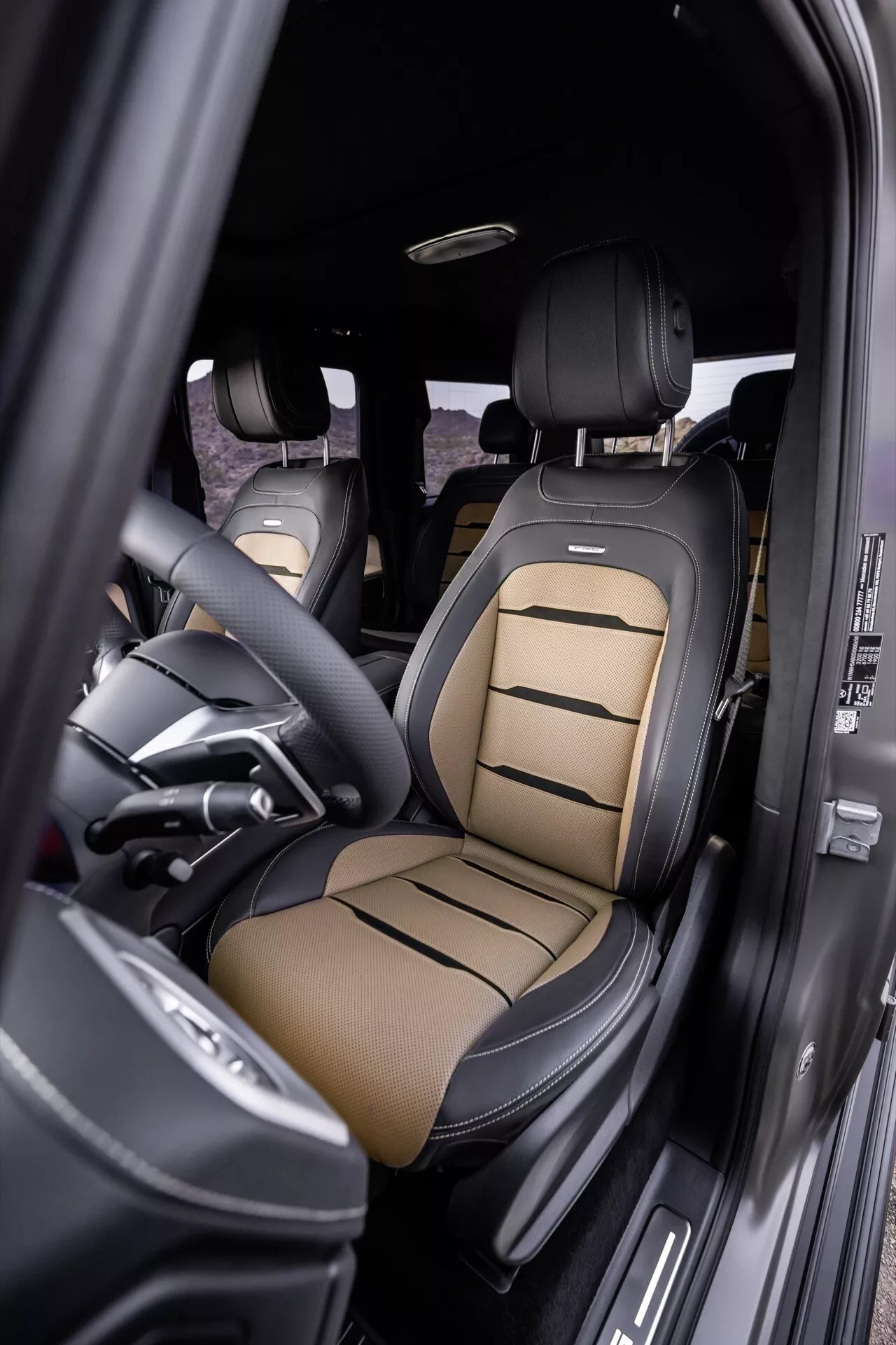 Vue intérieure de la Mercedes-Benz G-Klasse 2024 mettant en évidence le siège du conducteur avec une sellerie en cuir de luxe bicolore, des commandes avancées de réglage du siège et des éléments de design haut de gamme