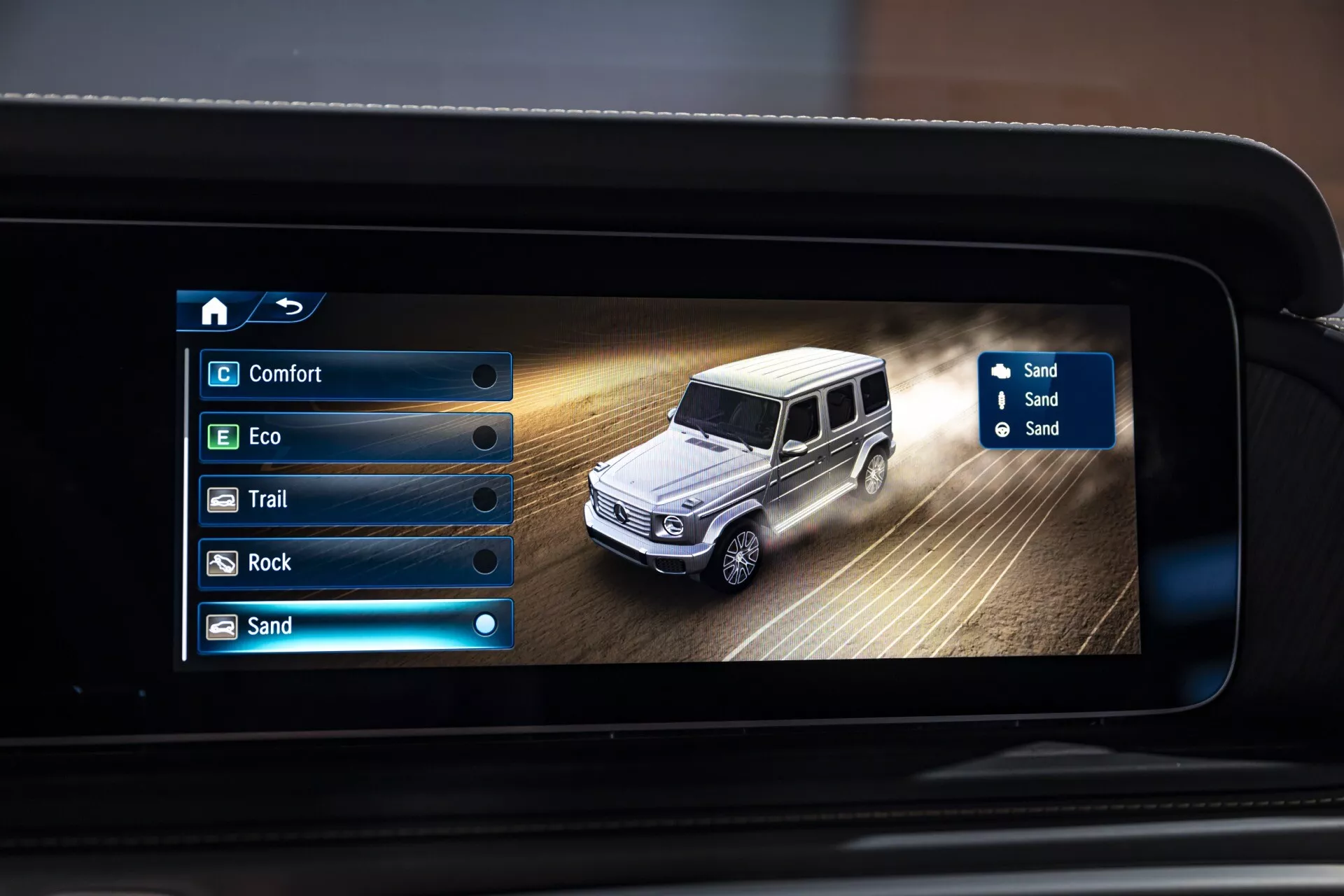 Écran du système d'infodivertissement Mercedes-Benz G-Klasse 2024 affichant le mode de conduite sur sable avec représentation digitale de la voiture