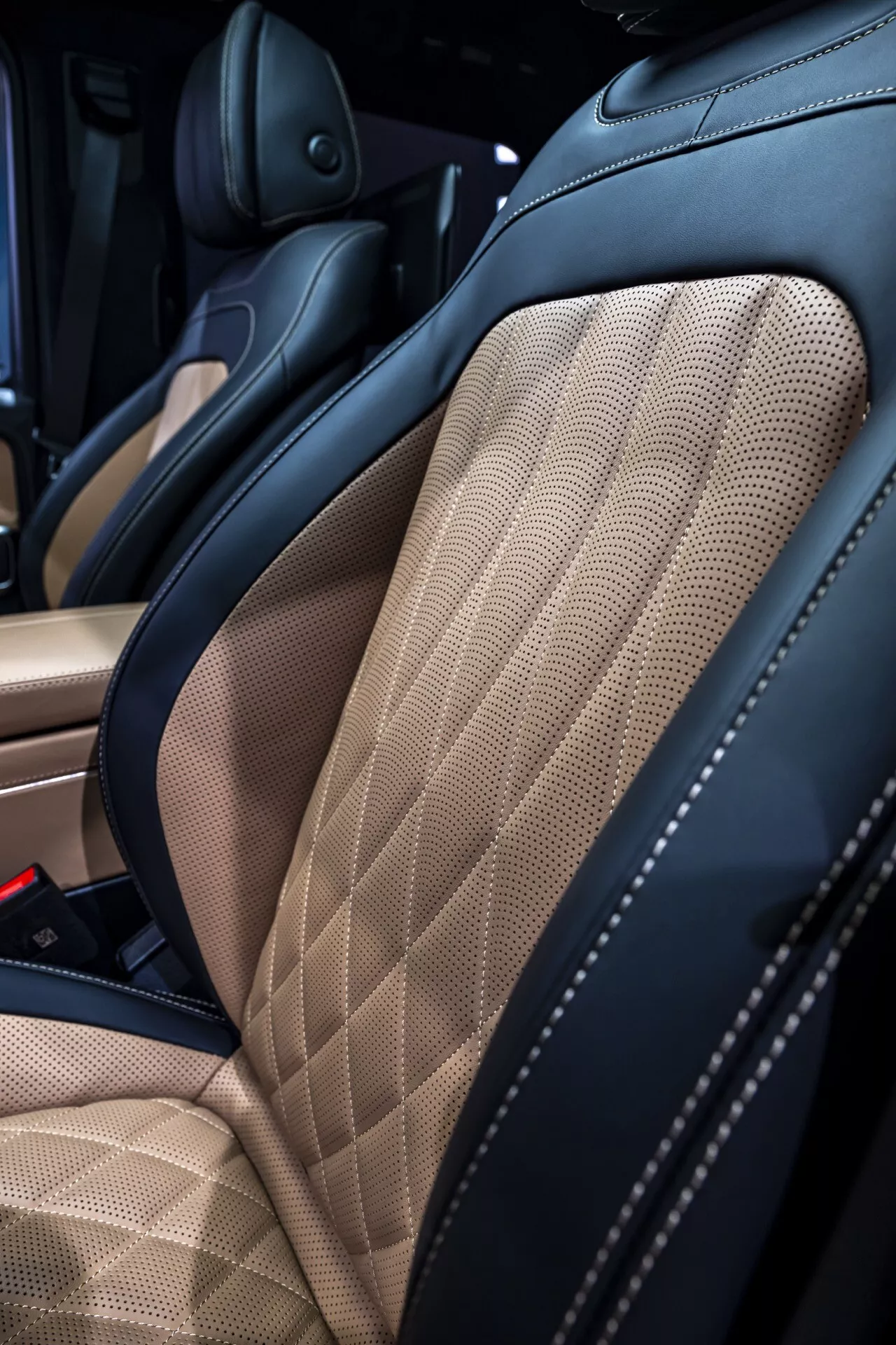 Vue rapprochée sur l'intérieur de la Mercedes-Benz G-Klasse 2024, mettant en lumière le siège en cuir bi-ton de haute qualité avec matelassage en diamant et un support latéral amélioré
