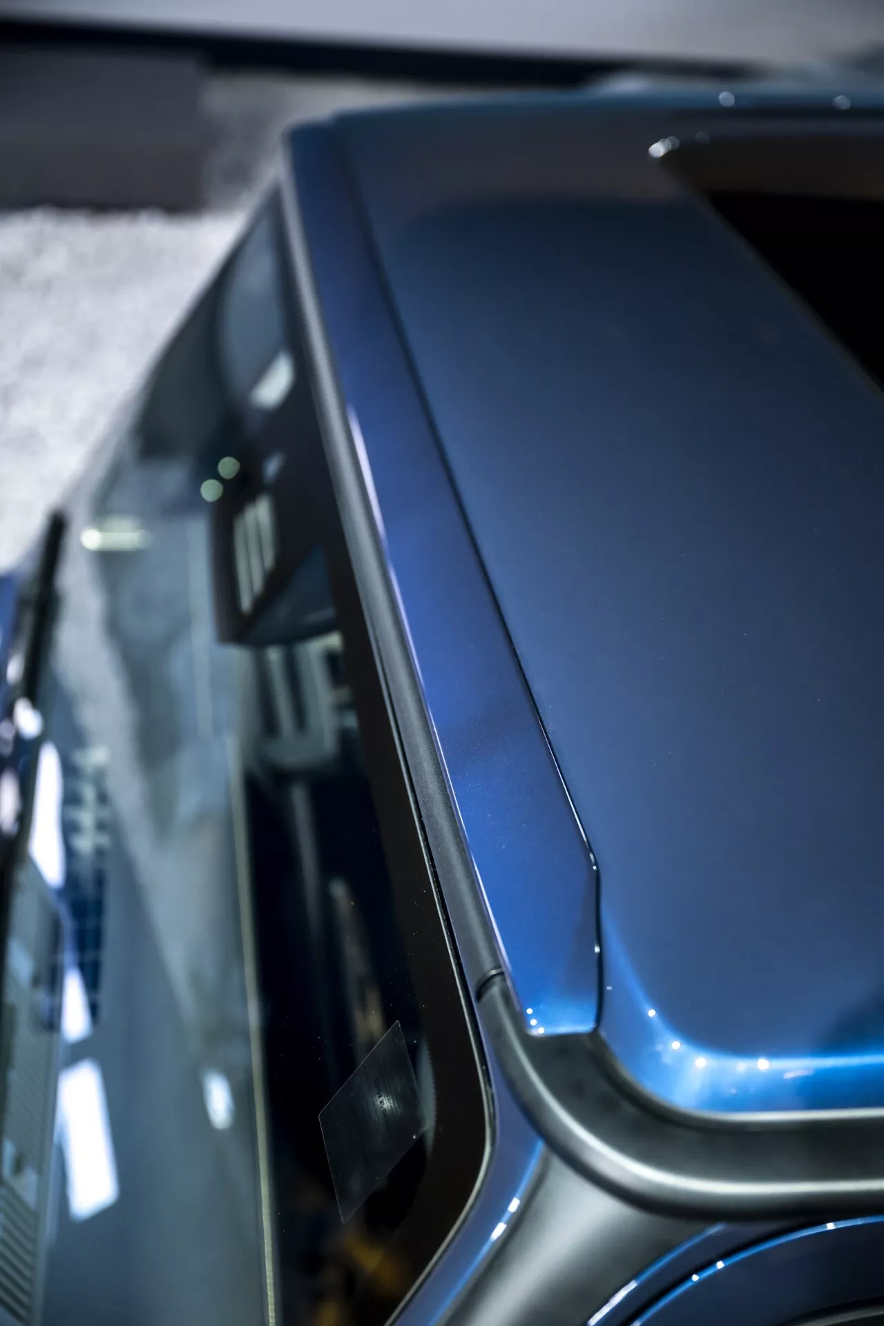Vue rapprochée du capot et du haut de l'aile de la Mercedes-Benz G-Klasse 2024 (465), mettant en avant sa courbure, les détails de conception et la finition métallique premium sous un angle élevé.