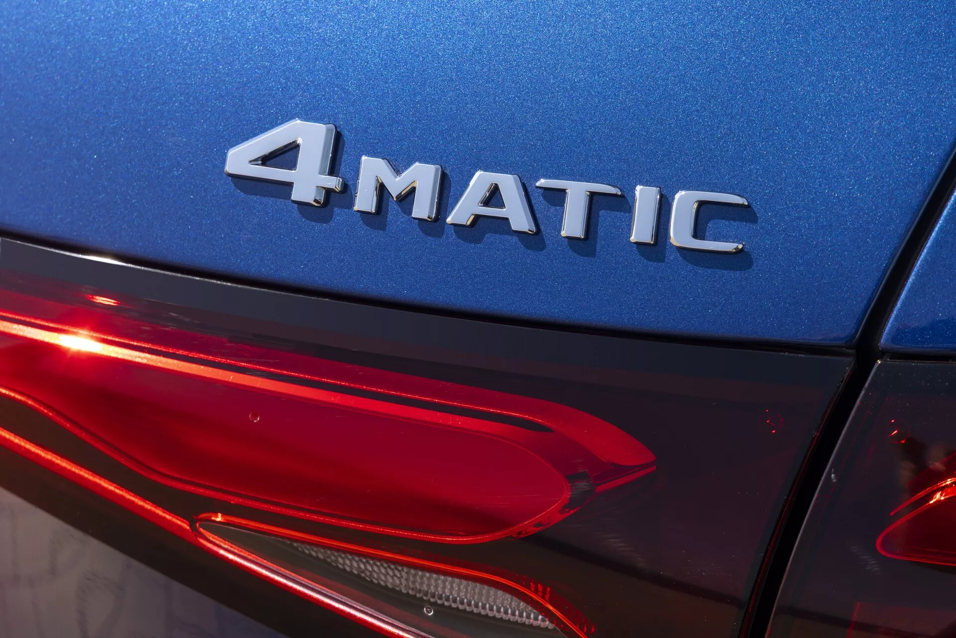 Gros plan sur le quart arrière d'une Mercedes GLC 2022 (254) sous un angle légèrement ascendant, avec l'insigne 4MATIC, la carrosserie bleu brillant et le design moderne des feux arrière à LED. Met en avant la technologie à quatre roues motrices, l'éclairage automobile et la finition extérieure de haute qualité.