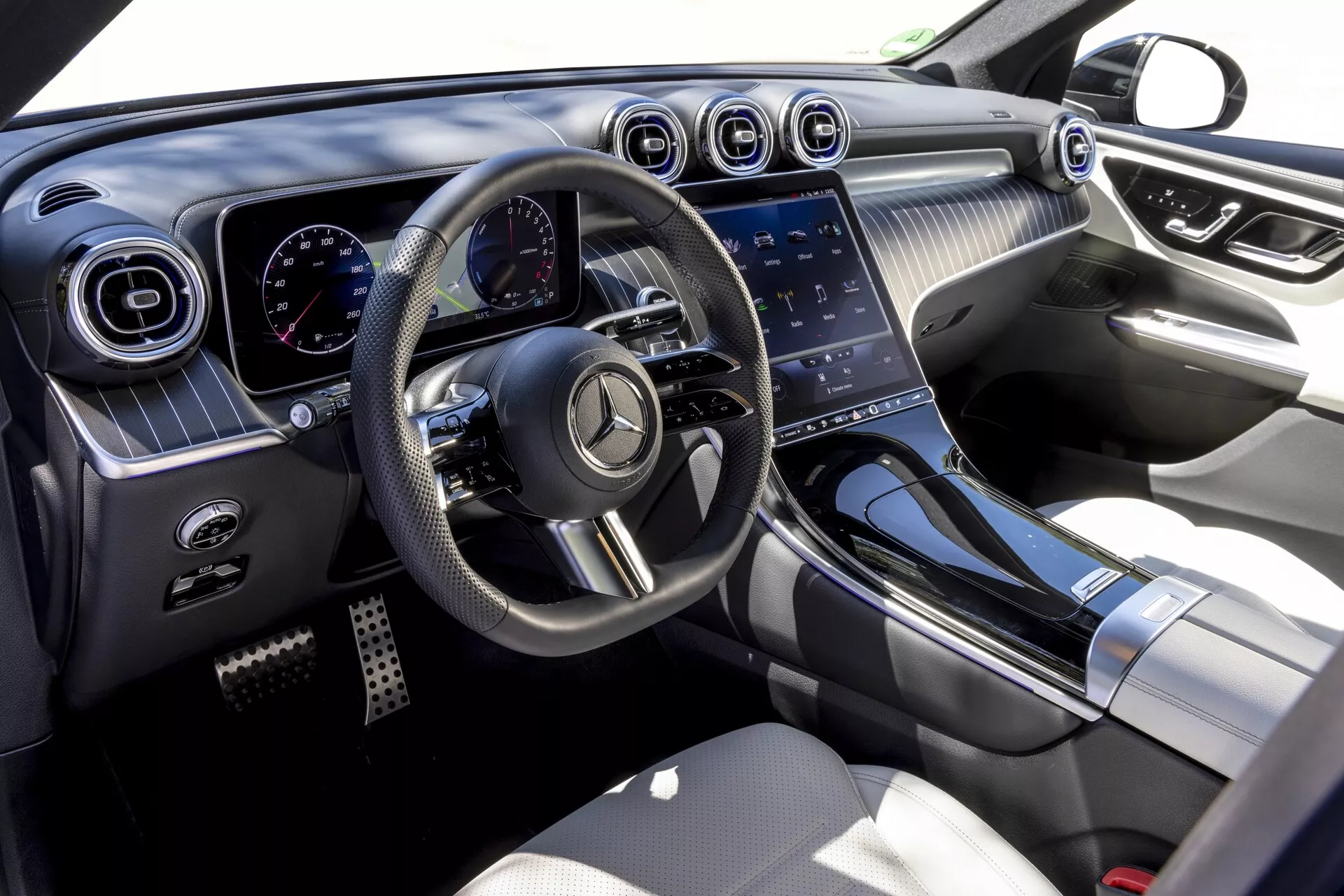 Vue intérieure du Mercedes GLC 2022 (254) depuis le côté passager, mettant en avant le design moderne et luxueux avec volant multifonction à fond plat, tableau de bord numérique, aérateurs circulaires avec accents chromés, grand système d'infodivertissement à écran tactile et matériaux de haute qualité tels que surfaces au toucher doux, accents métalliques et sièges en cuir.