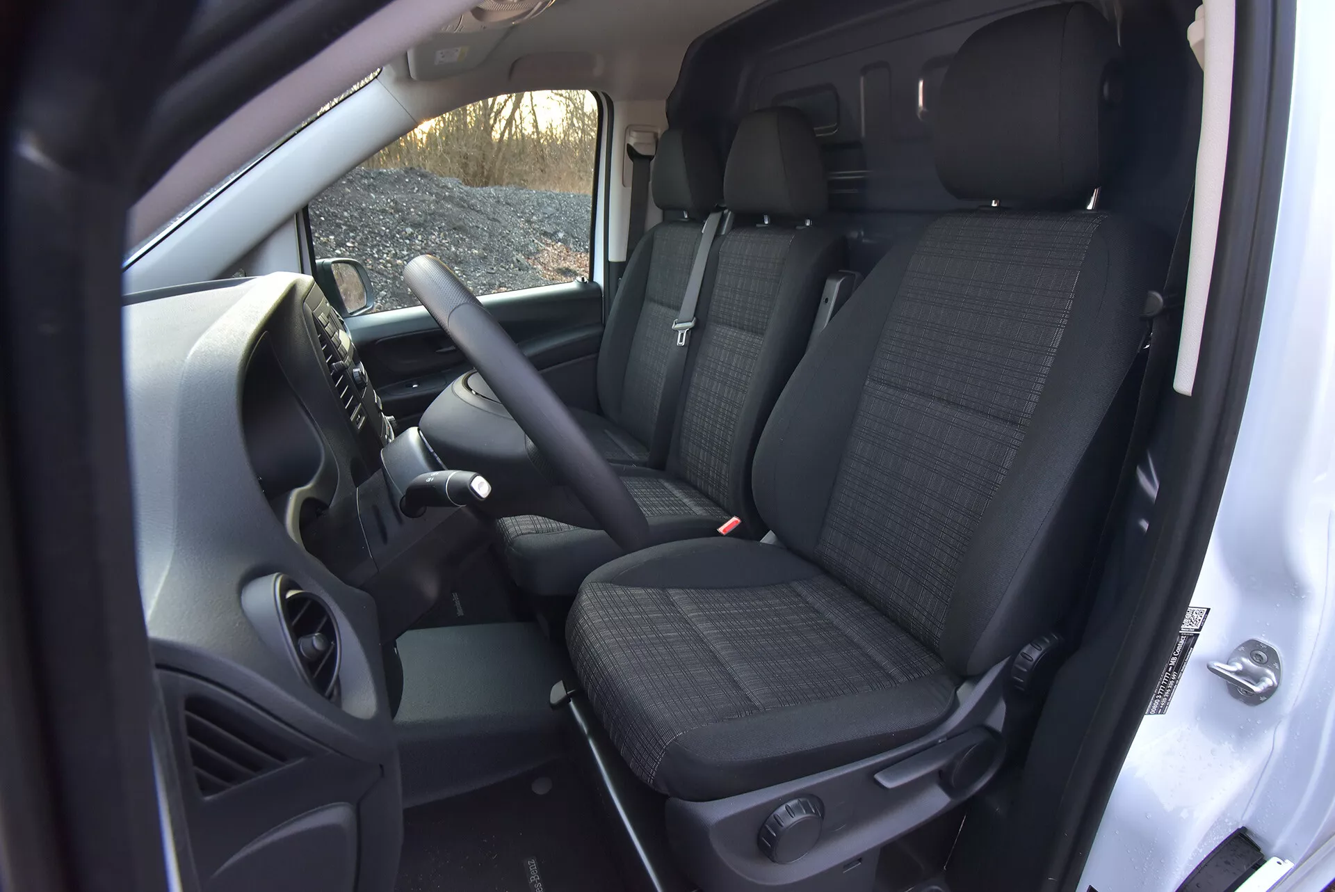 Vue intérieure du Mercedes-Benz Vito 2014 (Vito-Tourer) montrant la zone du conducteur et du passager avant avec des caractéristiques technologiques telles que des commandes montées sur le volant, une console centrale abritant potentiellement un système d'infodivertissement, des sièges avant en tissu à motifs avec appuie-têtes, et un aperçu des sièges arrière, le tout pris depuis un angle élevé mettant en lumière l'espace de la cabine et les éléments de transmission manuelle.