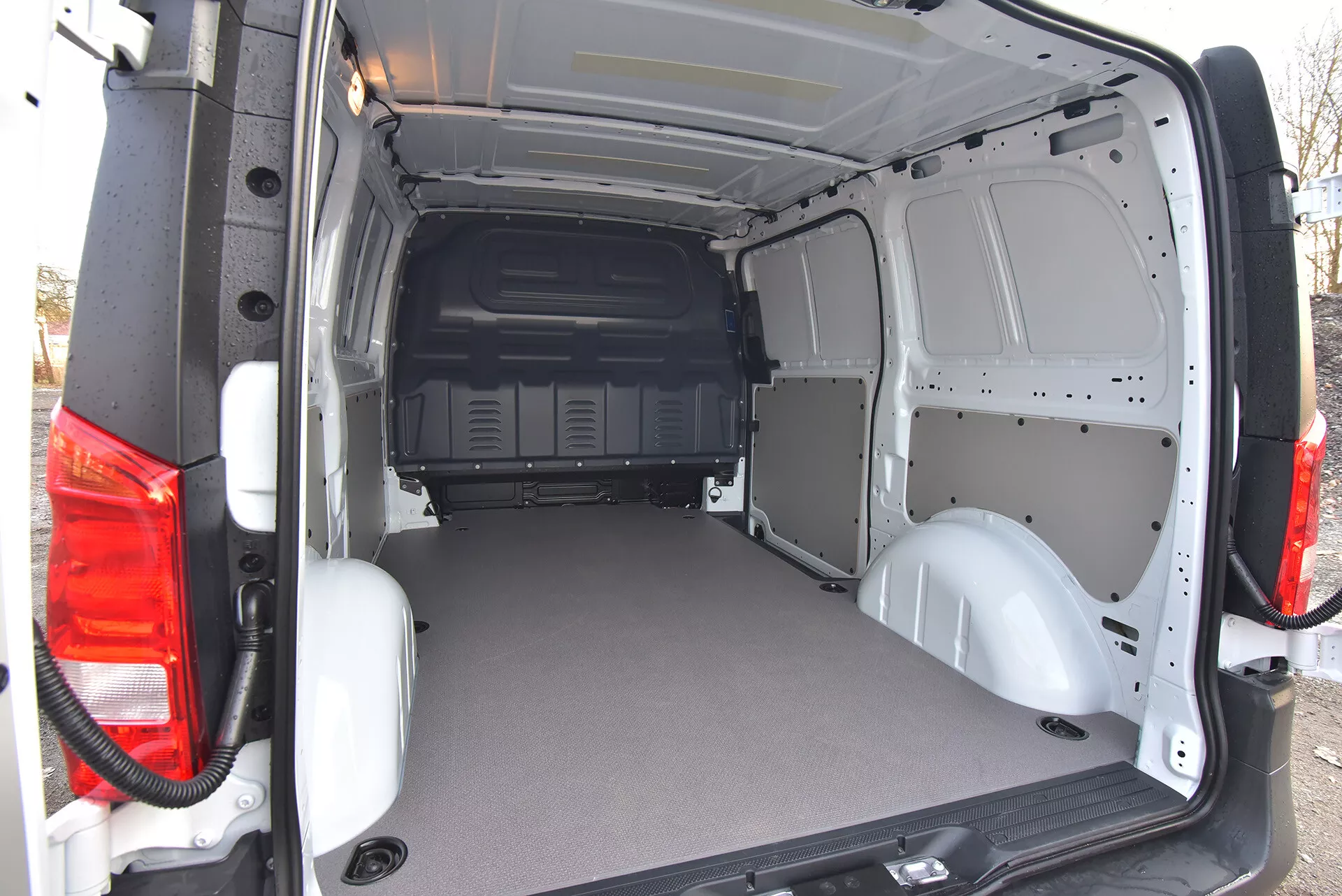 Zone de chargement arrière du fourgon commercial Mercedes-Benz Vito Tourer 2014 avec portes ouvertes montrant un sol plat durable et un intérieur en métal nu pour une personnalisation facile, vue d'un angle extérieur arrière oblique