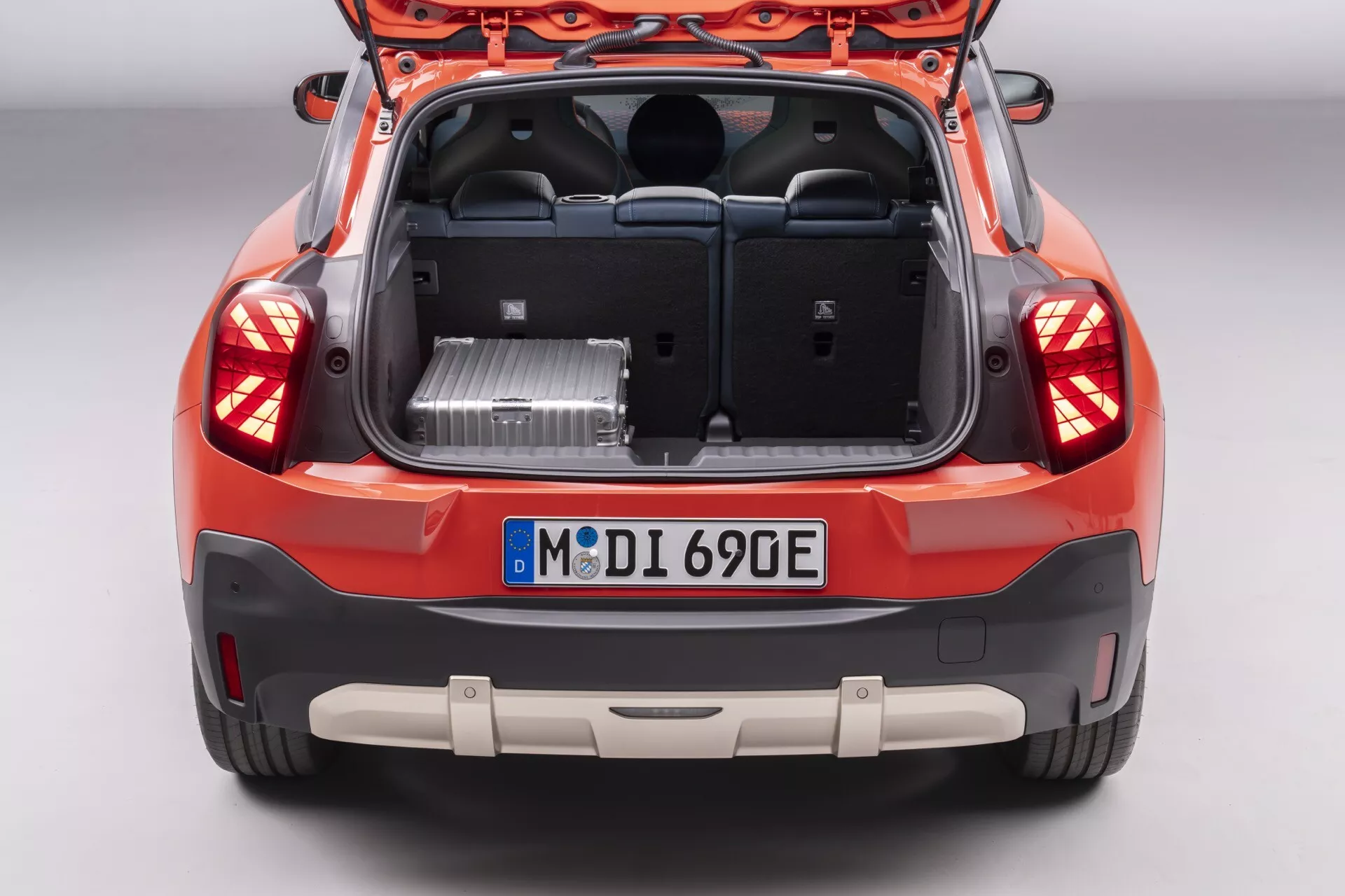 Vue arrière d'une Mini Aceman (J05) hatchback 2024 avec hayon ouvert, révélant l'espace de coffre spacieux et montrant les caractéristiques de conception arrière y compris les feux arrière, pare-chocs avec capteurs de stationnement, et badges indiquant la technologie électrique ou hybride, photographiée sous un angle surélevé.