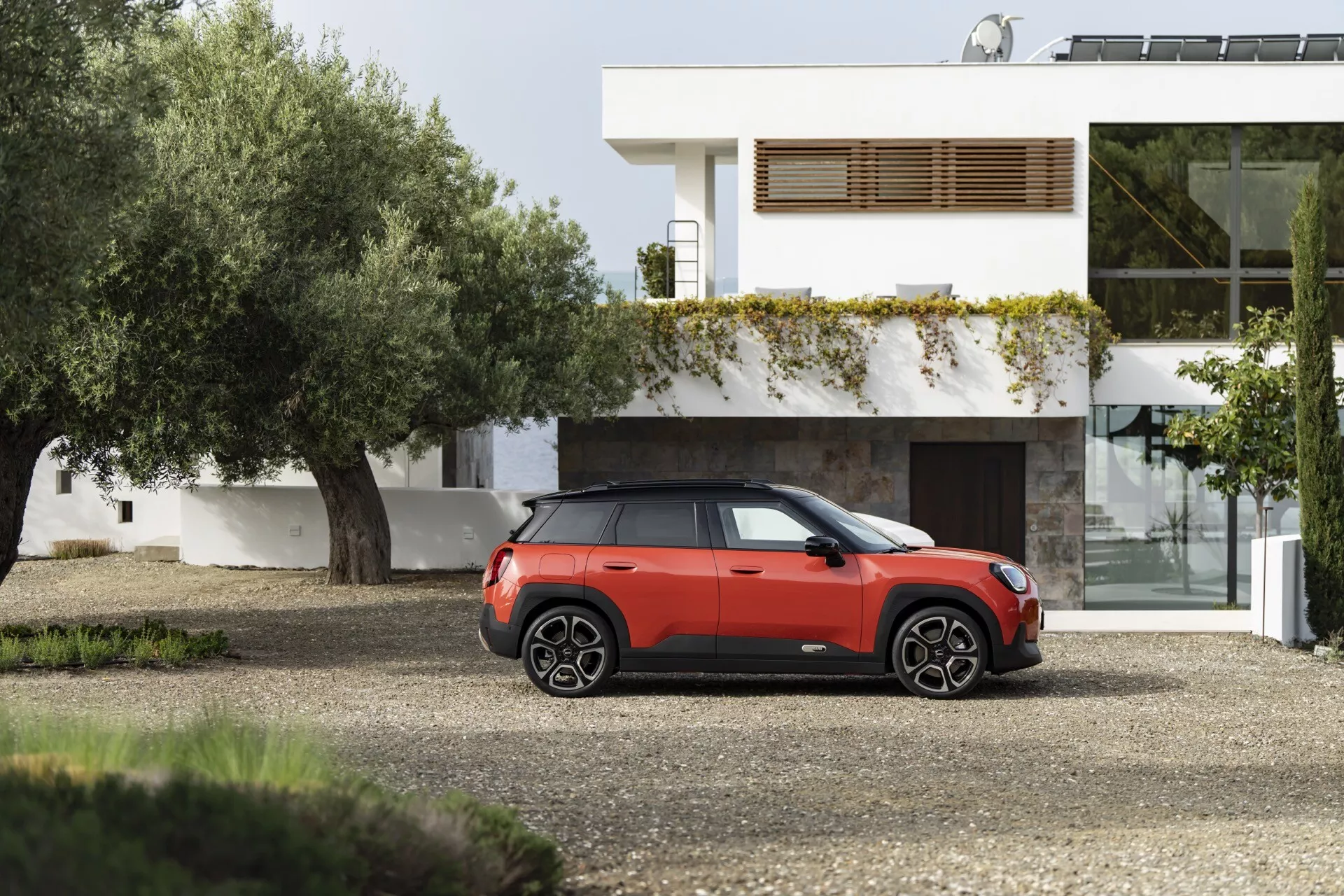 Mini Aceman 2024 (J05) garée devant une maison moderne montrant son profil latéral avec un toit contrasté, des jantes en alliage, des clignotants intégrés dans les rétroviseurs latéraux et des vitres teintées