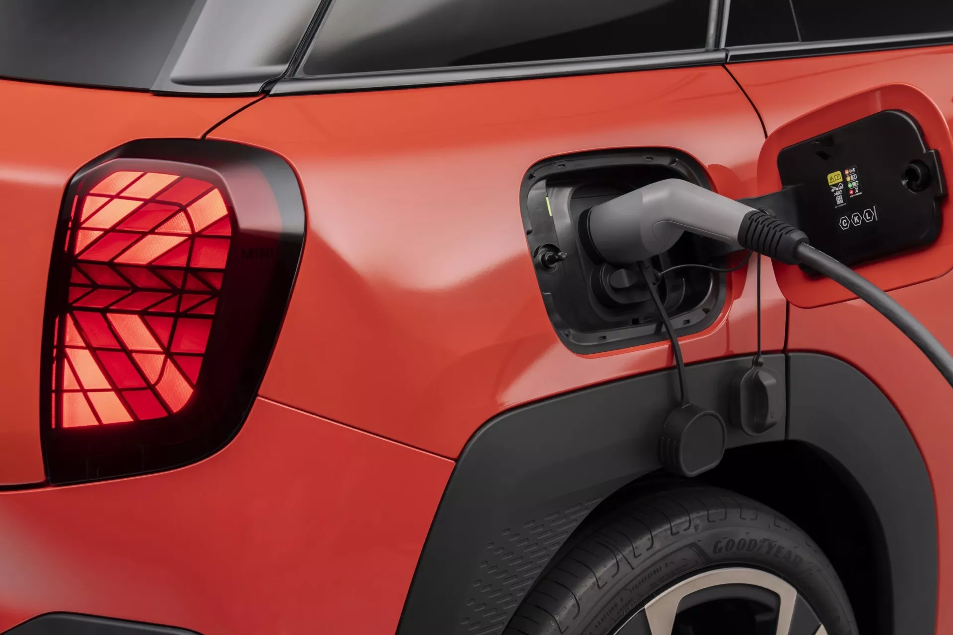 Véhicule électrique rouge Mini Aceman (J05) de 2024 en cours de charge, montrant de près le port de charge ouvert avec le câble connecté, les feux arrière LED et la roue arrière