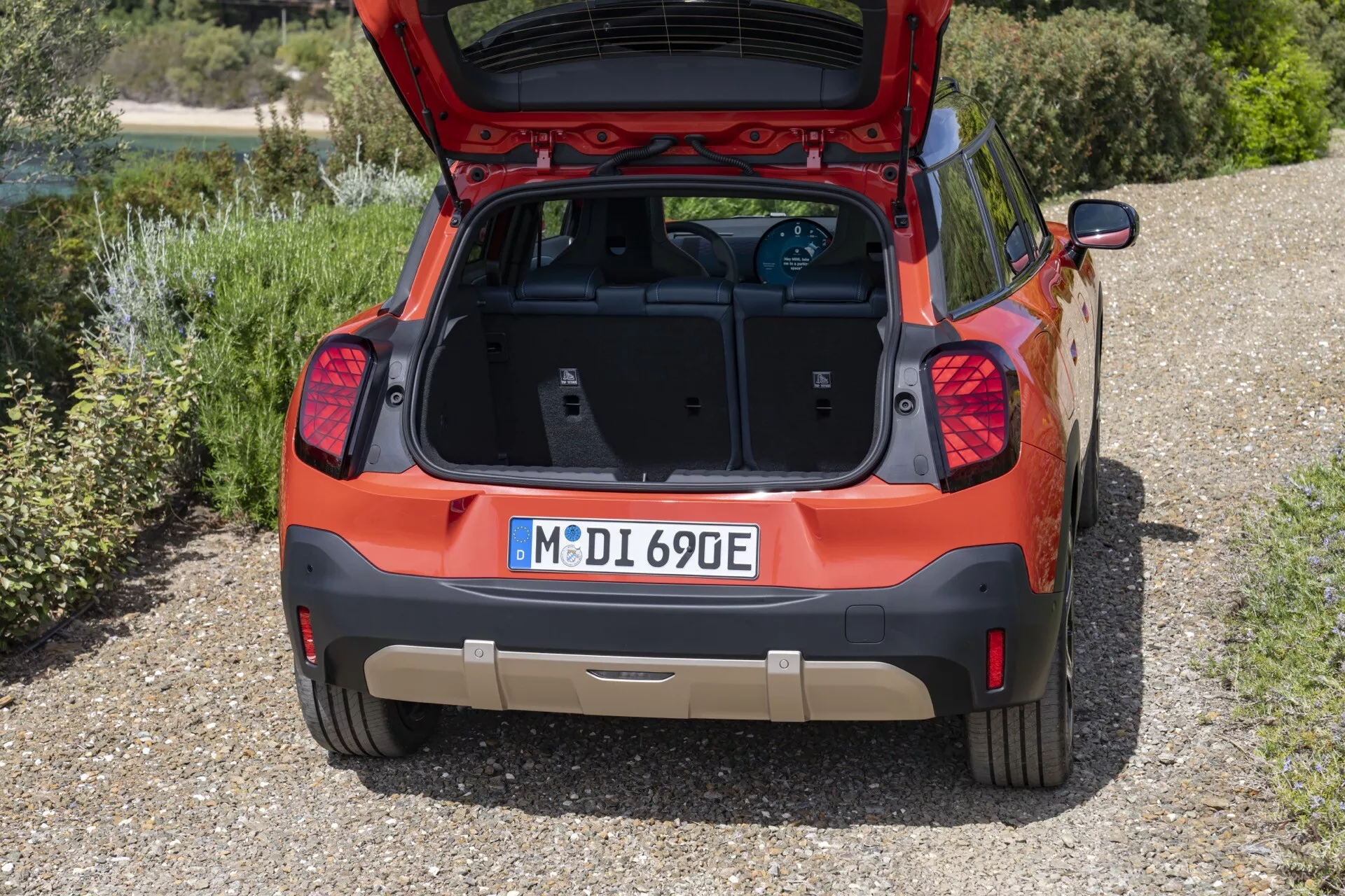 Vue arrière d'un crossover/SUV compact Mini Aceman (J05) 2024 présentant son coffre ouvert et son espace de chargement propre, feux arrière LED modernes, becquet arrière intégré profil bas, badge électrique/hybride, capteurs/caméra de stationnement, et peinture bicolore avec éventuelle plaque de protection