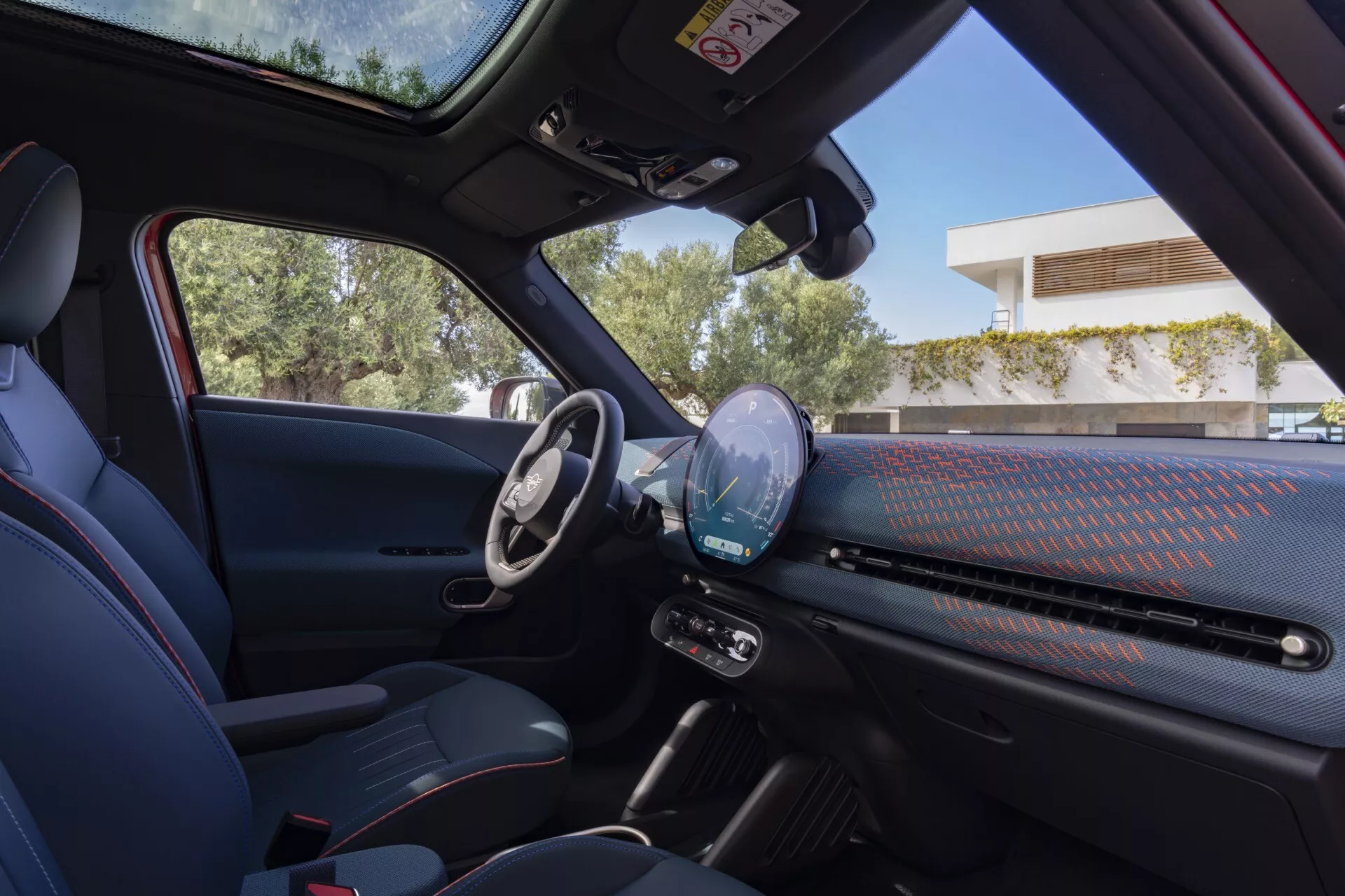 Vue intérieure du Mini Aceman (J05) 2024 depuis le siège arrière mettant en lumière le côté conducteur avec tableau de bord numérique, volant multifonction et éléments de design moderne