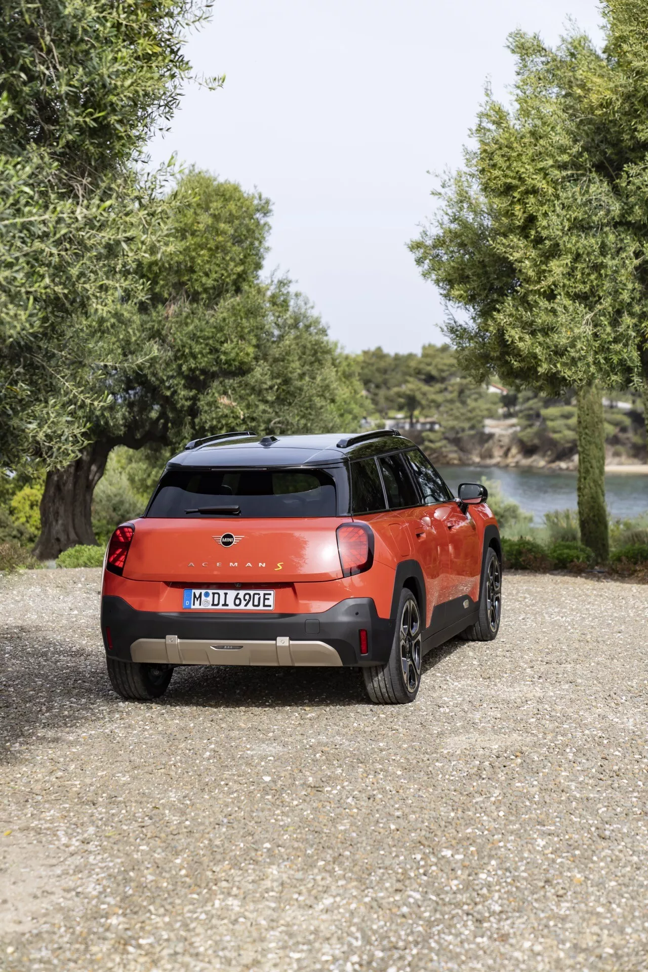 Vue arrière d'un SUV compact Mini Aceman 2024 en rouge vibrant avec toit noir, présentant des feux LED, des roues en alliage, et garé dans un cadre méditerranéen