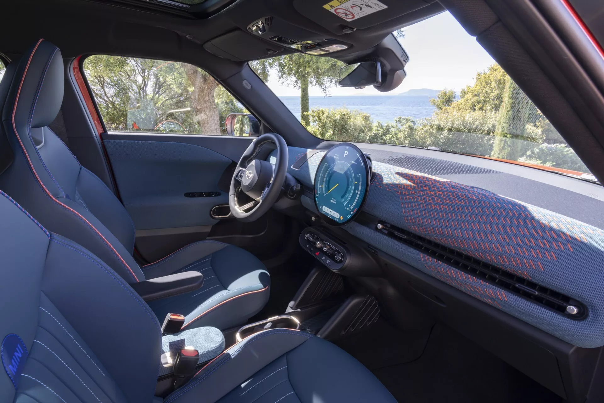 Vue intérieure du Mini Aceman 2024 (JO5) présentant le tableau de bord moderne avec un cluster d'instruments digital et un grand système d'infodivertissement tactile, sièges sportifs et éléments de design minimaliste