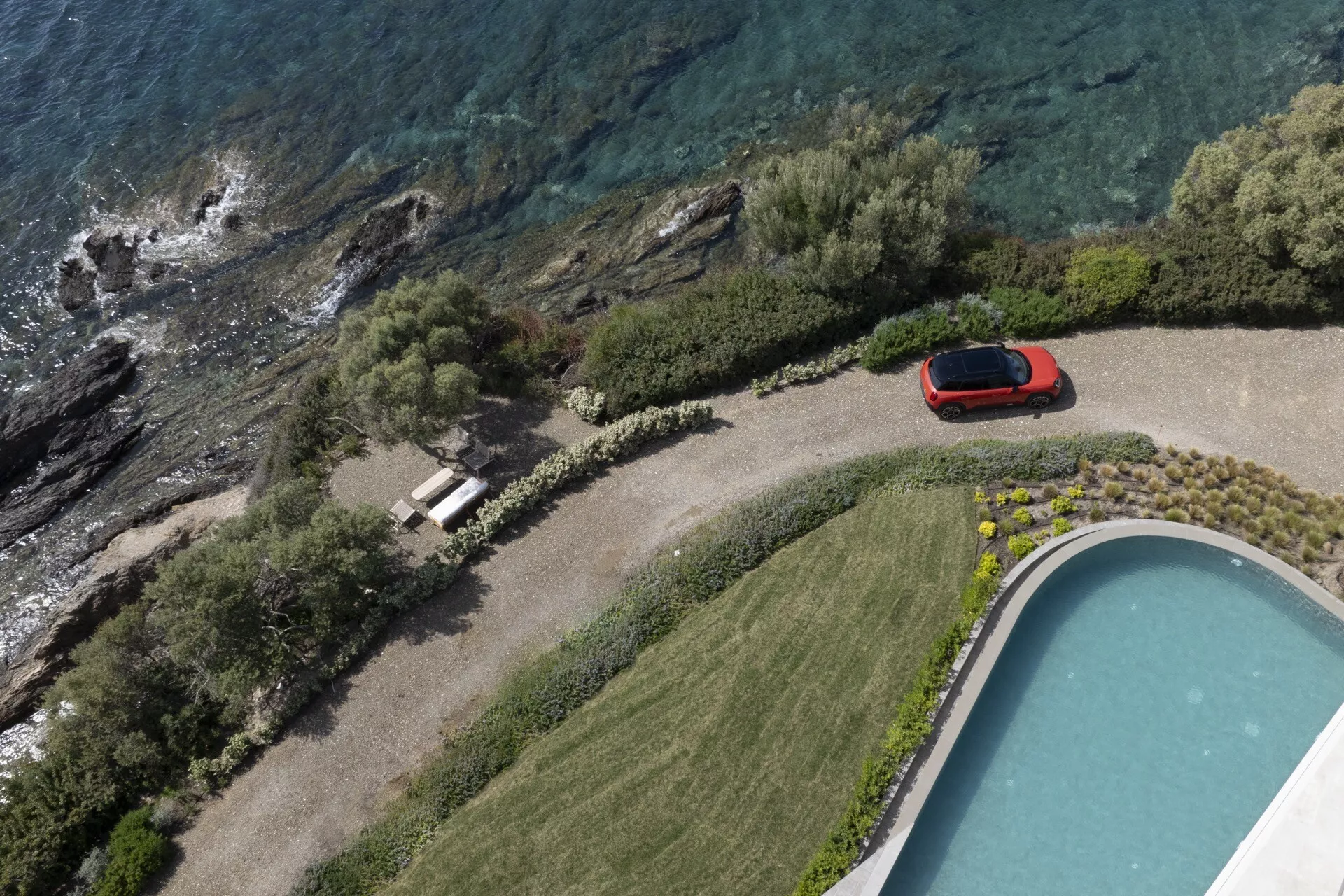 Mini Aceman (J05) 2024 en rouge, vue aérienne en plongée garée à côté d'une piscine, présentant son design élégant et sportif et sa finition brillante dans un cadre luxueux