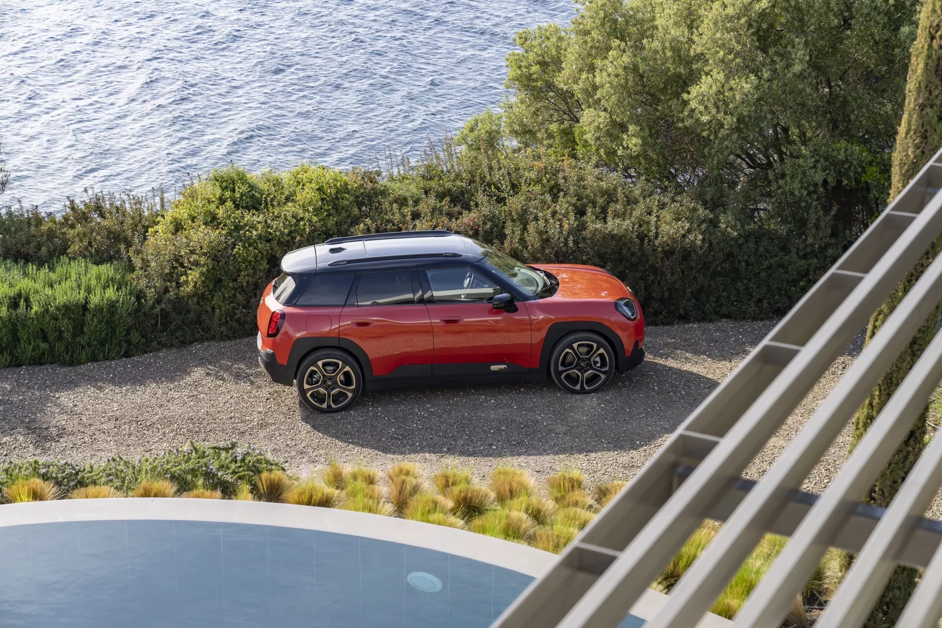 Mini Aceman (J05) 2024 capturé depuis un angle élevé, mettant en avant son design SUV moderne avec un schéma de couleurs bicolore sur une surface en gravier près de la côte, mettant en évidence des vues latérales et supérieures avec des détails de roues en alliage à plusieurs branches, un spoiler sportif et la technologie LED dans un cadre extérieur côtier