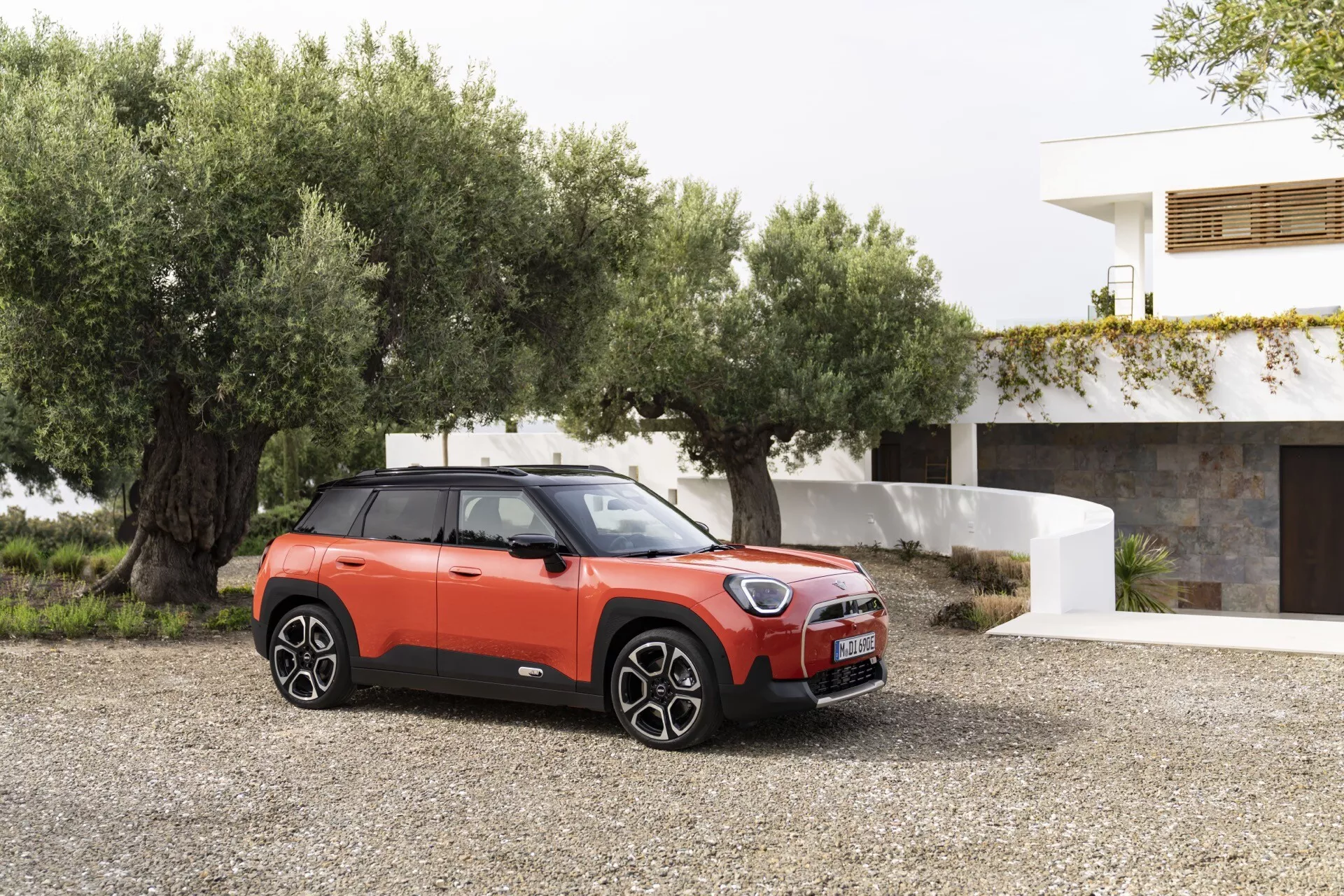 Mini Aceman 2024 (J05) en orange vif avec toit noir contrastant et design sportif, doté de roues en alliage, de garnitures noires robustes et d'un toit panoramique, garée dans un cadre contemporain