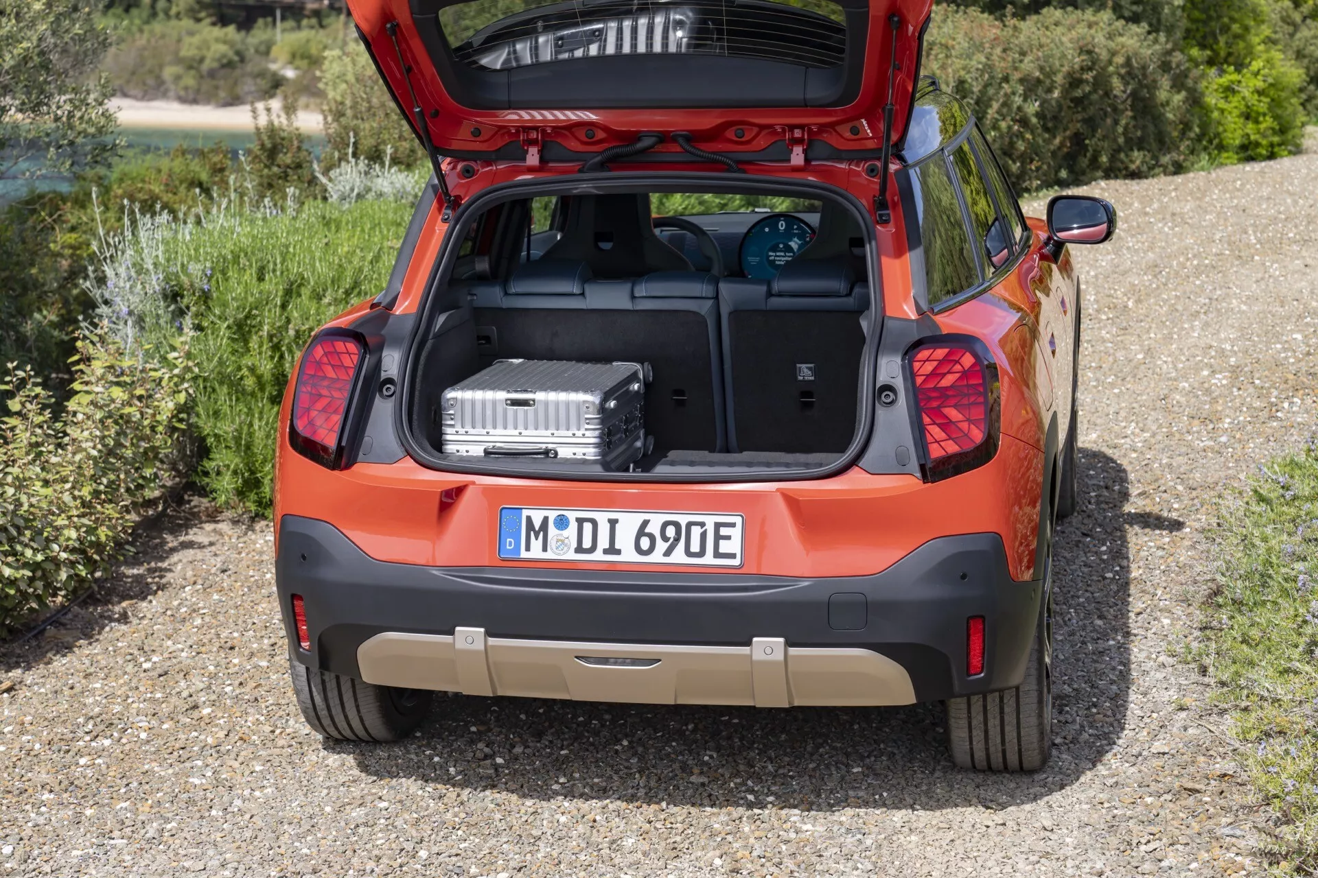 Vue arrière du Mini Aceman 2024 (J05) présentant un coffre spacieux, des indices de motorisation électrique/hybride et une finition orange vibrante dans un cadre extérieur