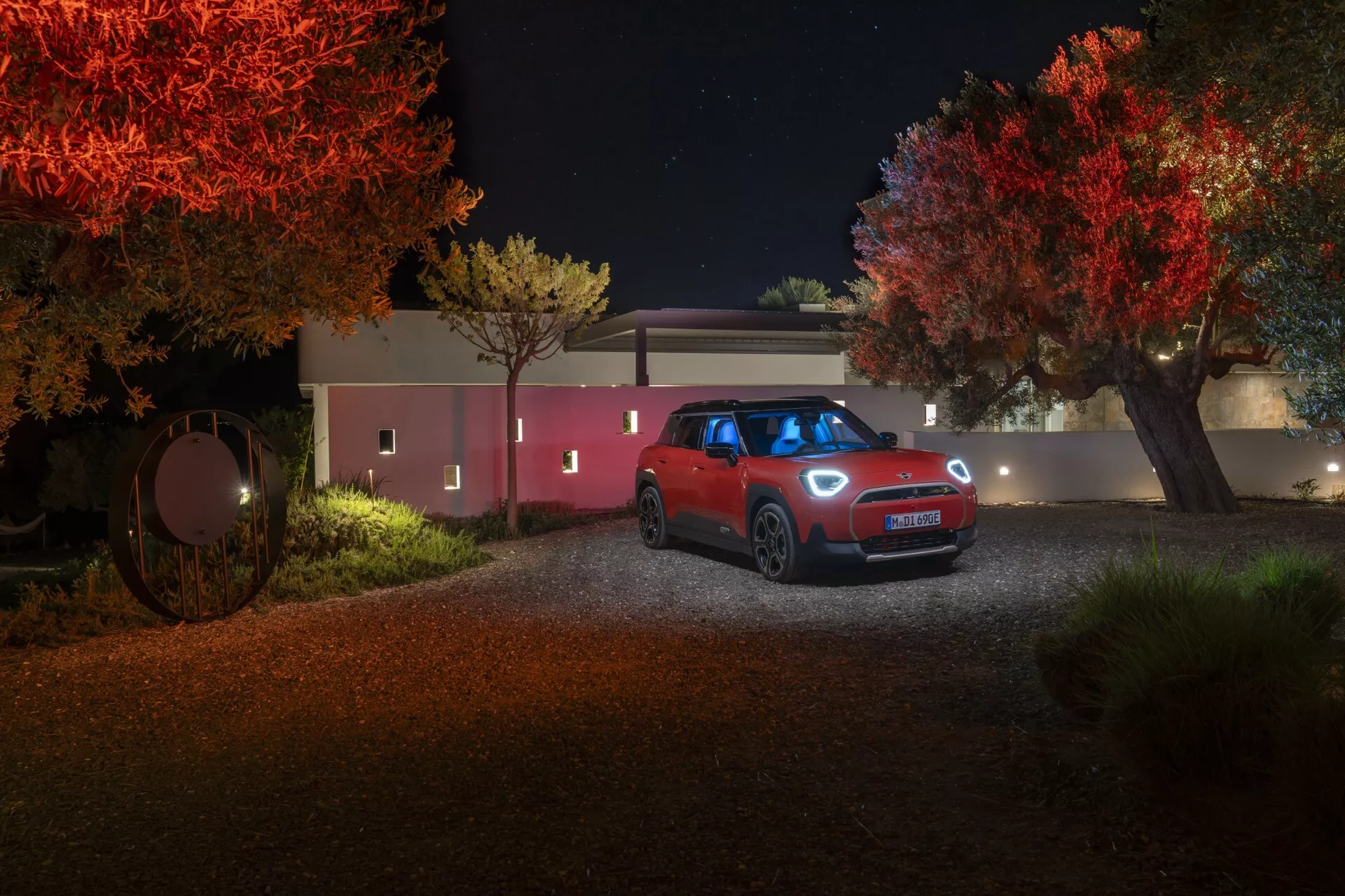Vue frontale nocturne du SUV compact Mini Aceman (J05) 2024 sur un chemin rural avec des arbres illuminés