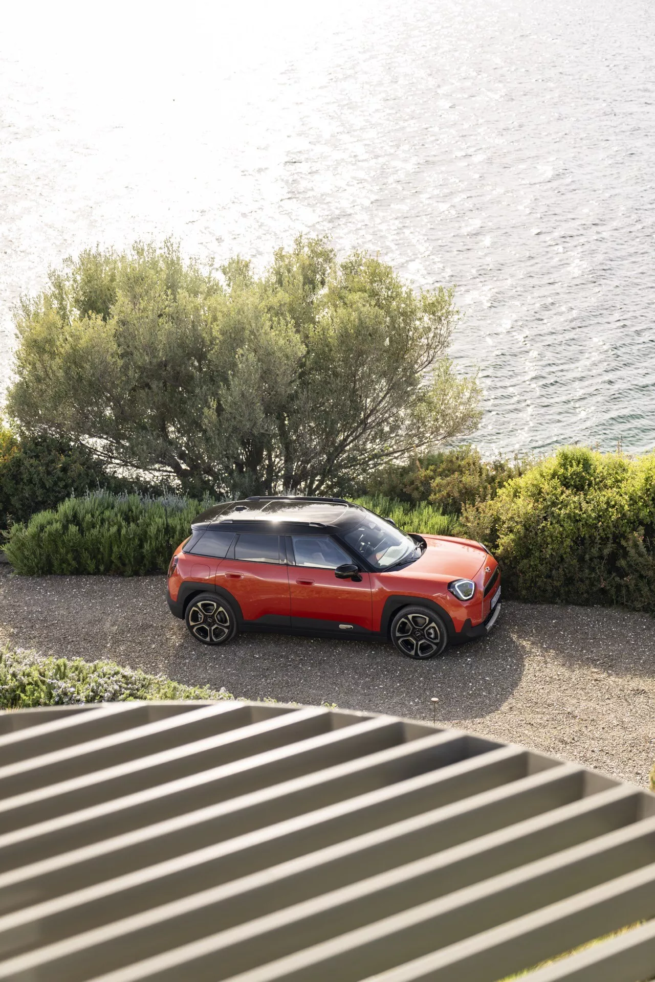 Mini Aceman (J05) 2024 en rouge et noir, vue de haut, présentant des roues en alliage élégantes, des phares LED modernes et une peinture bicolore, garée au bord du rivage