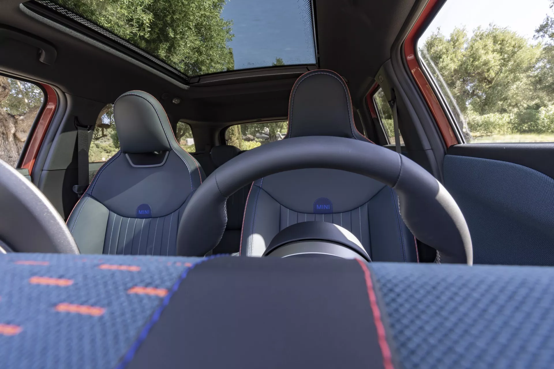 Vue intérieure du Mini Aceman 2024 (J05) montrant les sièges avant, le volant et le toit panoramique depuis la perspective du siège arrière, mettant en évidence le design de la sellerie et les caractéristiques modernes