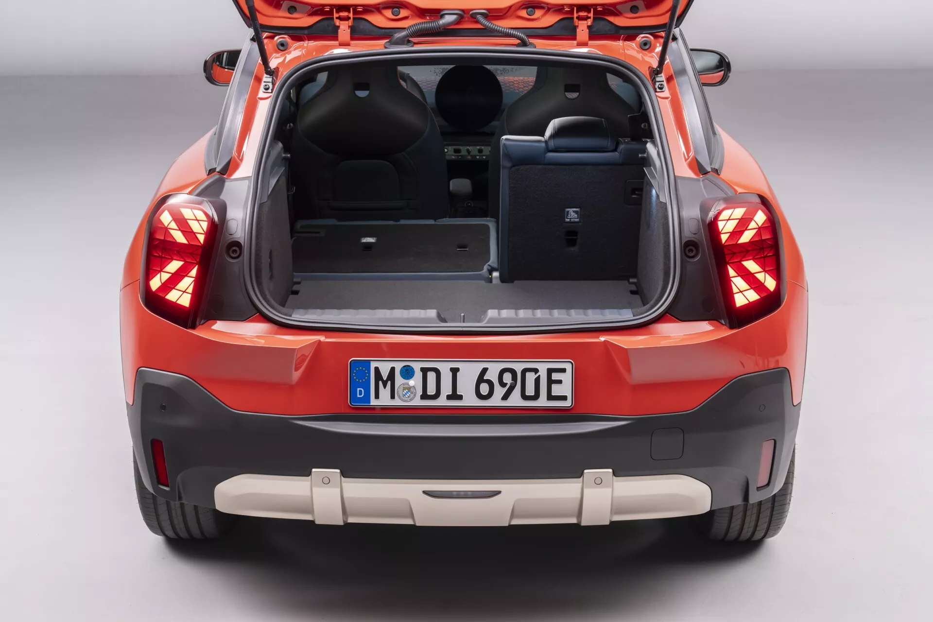 Vue arrière du Mini Aceman (J05) 2024 mettant en évidence son coffre spacieux avec hayon ouvert, détails de garniture intérieure, capteurs de stationnement intégrés sur le pare-chocs et ensemble d'éclairage arrière avancé, stationné dans un cadre d'exposition