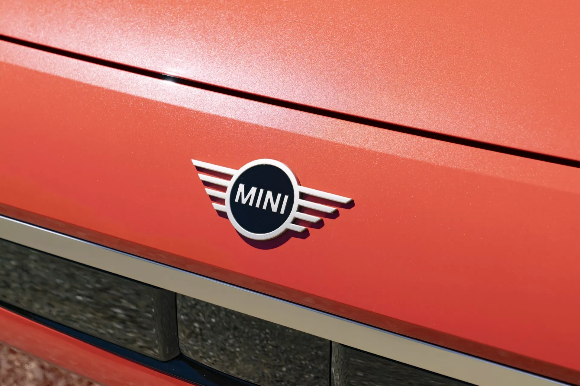 Gros plan sur le hayon arrière du MINI Aceman 2024 (J05) en rouge métallique vif avec le logo iconique de MINI, suggérant l'élégance et la vitesse du véhicule