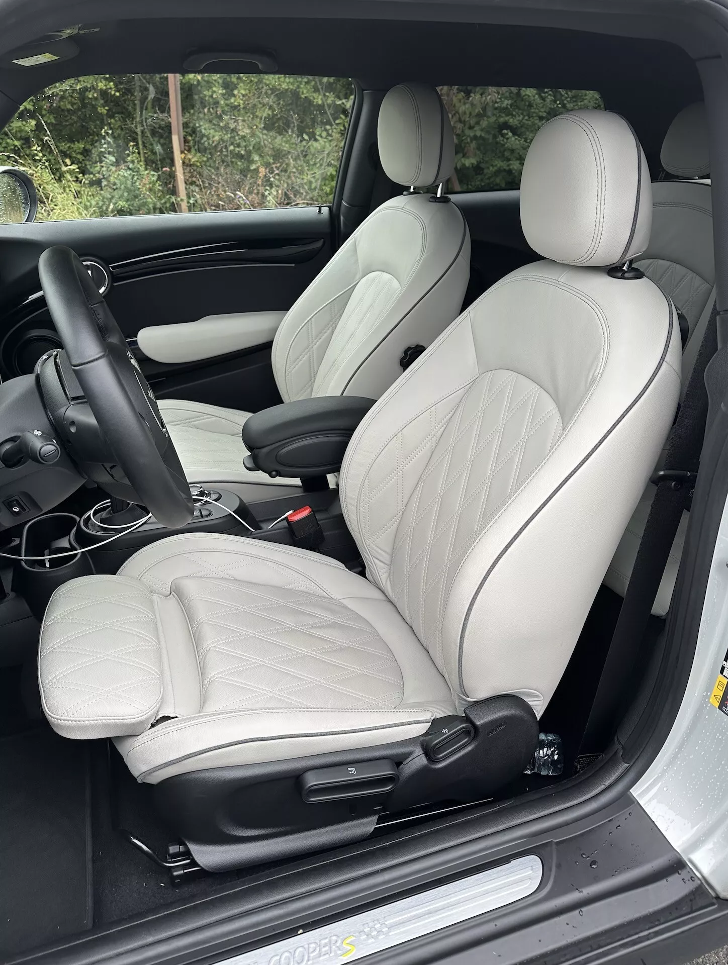 Vue intérieure de la Mini Electrique 3 Portes 2021 sur le siège conducteur en cuir de couleur claire avec renforts latéraux et commandes de réglage électrique, disposée avec tableau de bord conduite à gauche, montrant des éléments de luxe ergonomique et sportifs