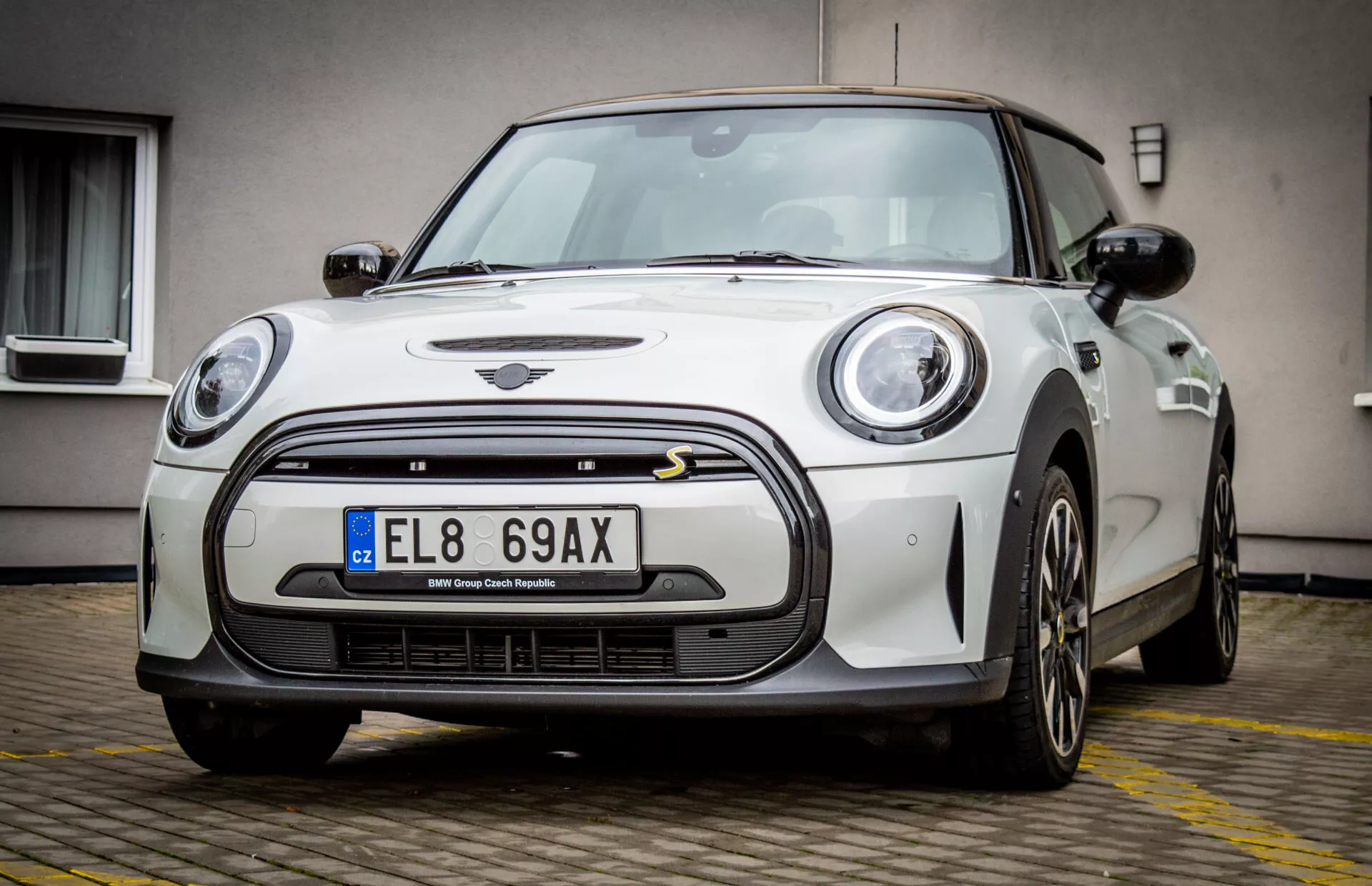 Mini Électrique 3 portes 2021 présentant son design moderne avec phares LED, grille noire entourée de chrome et prises d'air sur le pare-chocs avant, vue sous un angle avant bas de trois quarts soulignant sa stance sportive et ses proportions