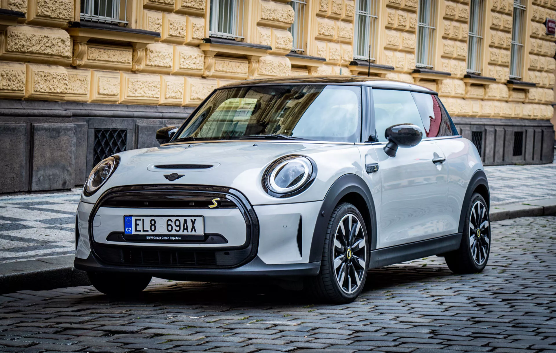 Modèle Mini Électrique 3 portes de 2021 sur rue pavée mettant en vedette calandre avant, phares ronds, toit contrastant et design moderne