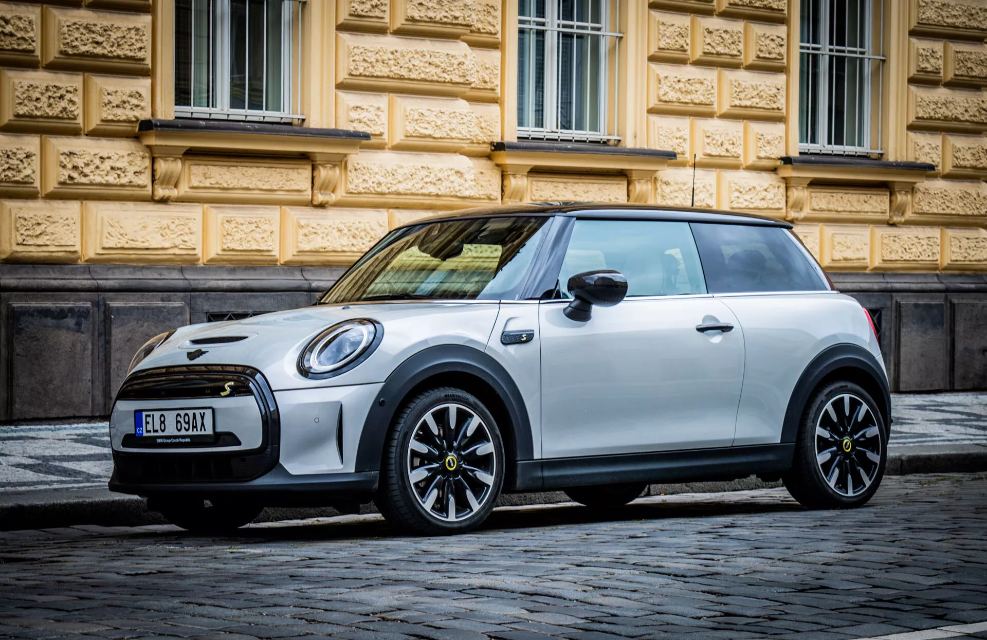 Mini Électrique 3 portes hatchback de 2021 garée sur une rue pavée, montrant un profil latéral mettant l'accent sur les roues en alliage et le design épuré et courbé caractéristique de Mini, dans des conditions d'éclairage favorables