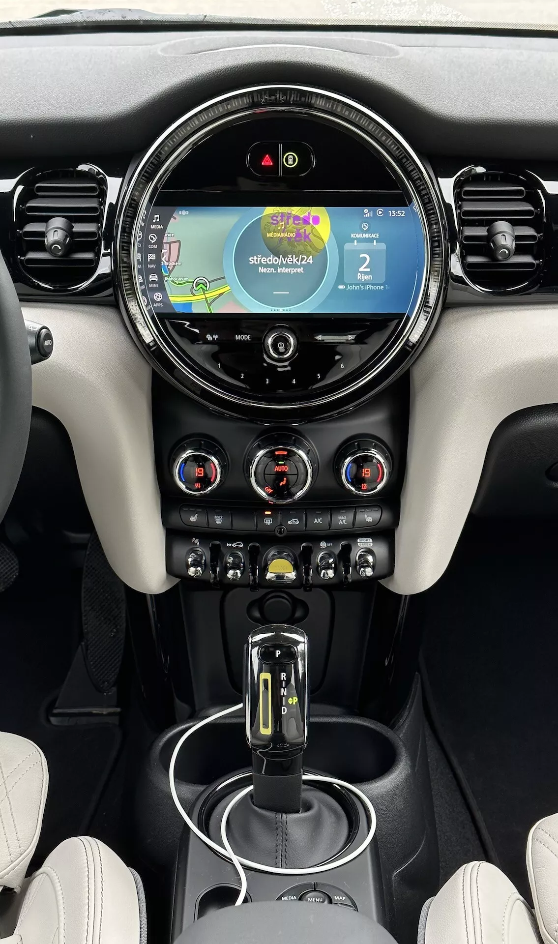 Vue intérieure d'une Mini électrique 3 portes de 2021, centrée sur la console centrale et le tableau de bord comportant un écran tactile avec navigation, contrôle climatique bi-zone et sélecteur de vitesse