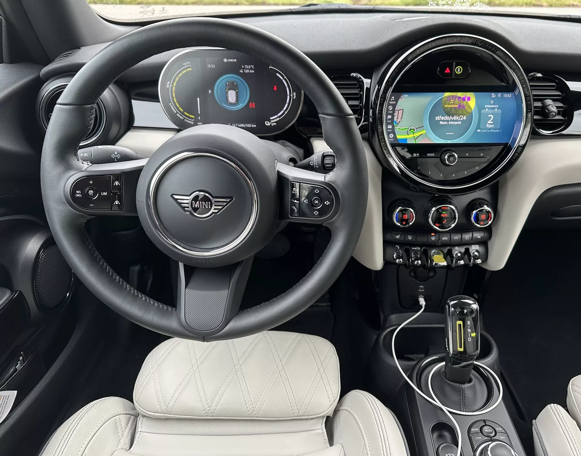 Intérieur du Mini Électrique 3 Portes 2021 avec volant avec logo et commandes, tableau de bord numérique, système d'infodivertissement tactile avec navigation, commandes de climatisation, levier de vitesse automatique, et sièges en cuir matelassé
