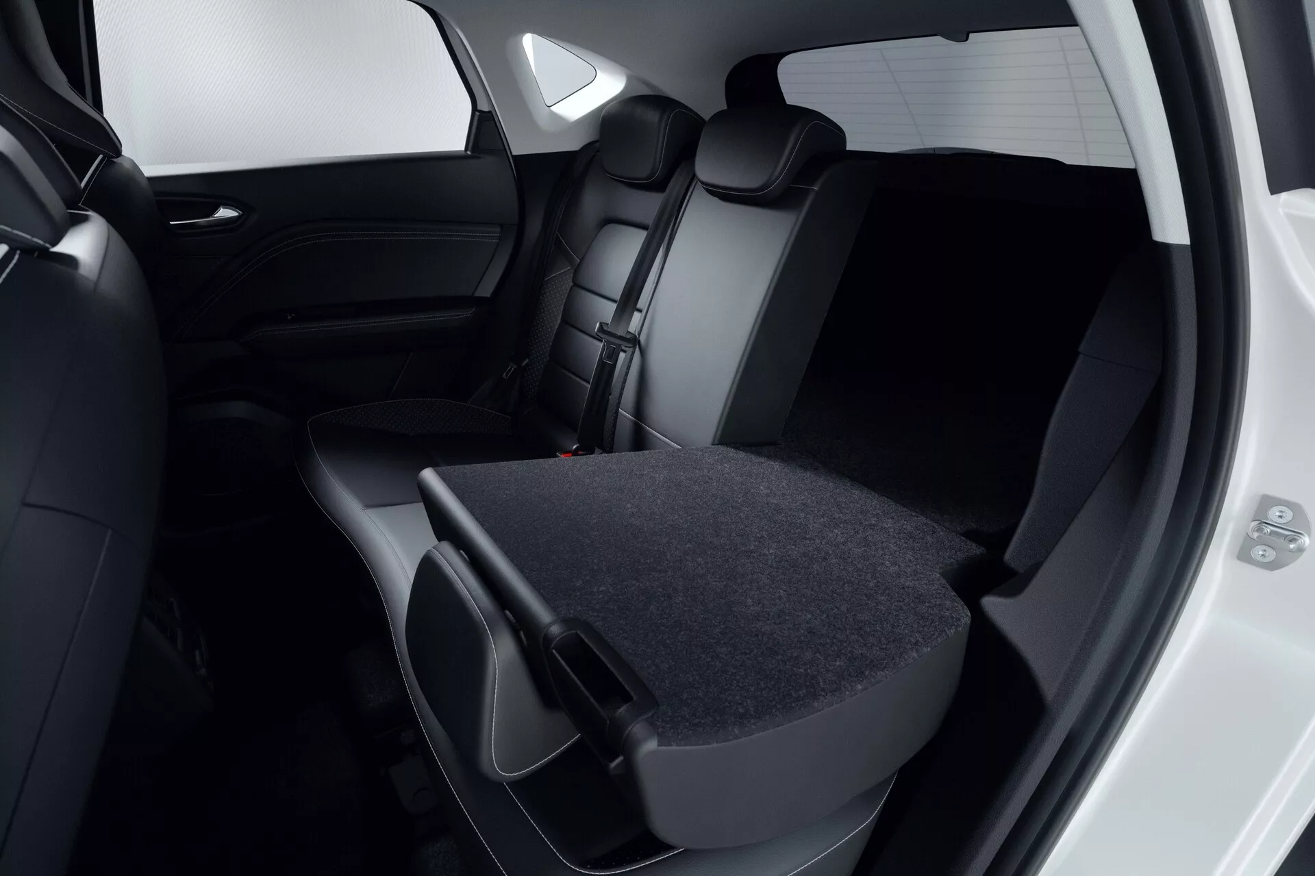 Vue rapprochée de l'intérieur arrière du Mitsubishi ASX 2023 (2e génération). Focalisation sur les sièges en cuir ou similicuir sombre, où le siège arrière droit est rabattu, montrant la flexibilité de chargement. La porte arrière est ouverte, révélant un intérieur sombre assorti et des vitres teintées. Le design moderne et minimaliste est évident dans la palette de couleurs noires ou gris foncé. L'image met en évidence la capacité de stockage du véhicule et l'engagement pour la sécurité avec des appuie-têtes et des ceintures de sécurité visibles.
