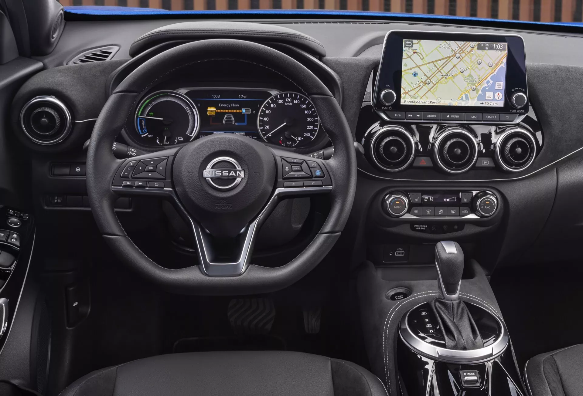 Vue intérieure d'un Nissan Juke (F16) de 2019 mettant en évidence le tableau de bord, le volant multifonction à trois branches avec logo NISSAN, le combiné d'instruments digital-analogique, le système d'infotainment tactile avec navigation, le contrôle climatique bi-zone et la zone du levier de vitesse automatique.